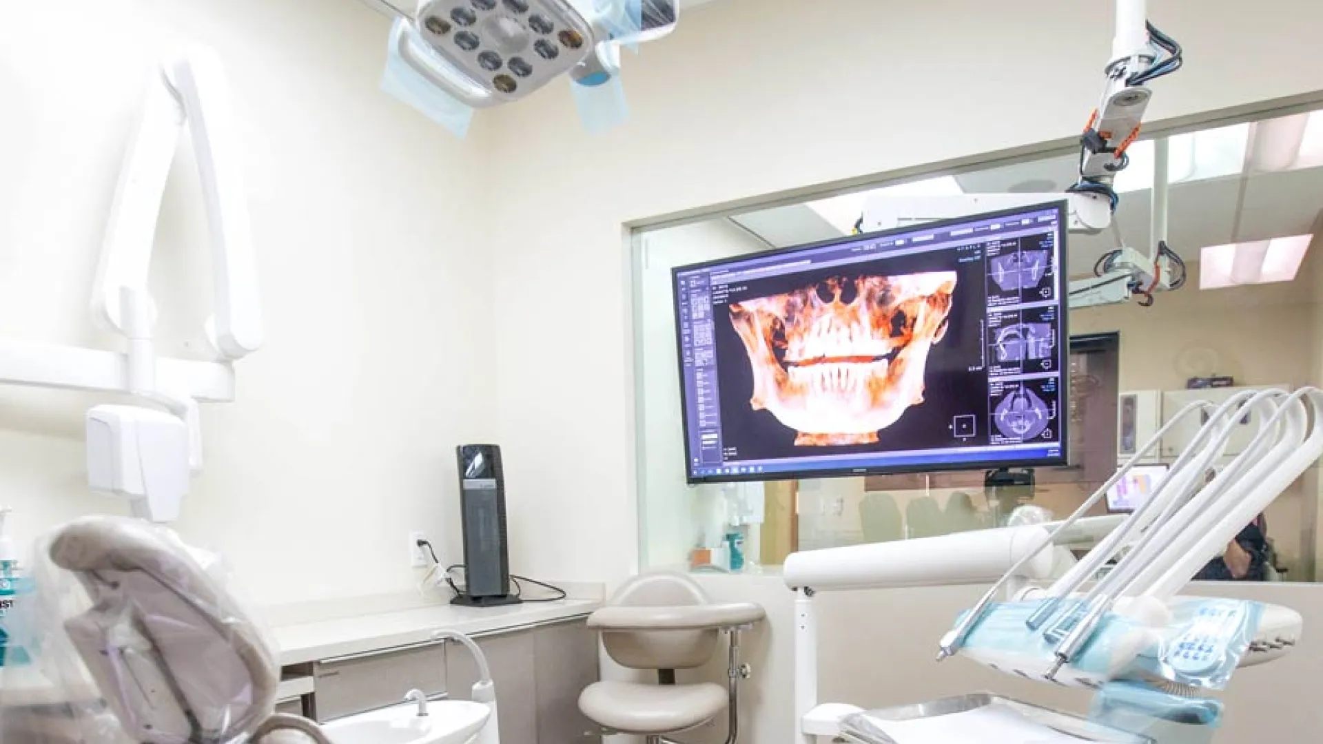 Modern dental clinic interior with examination chair and advanced imaging equipment.