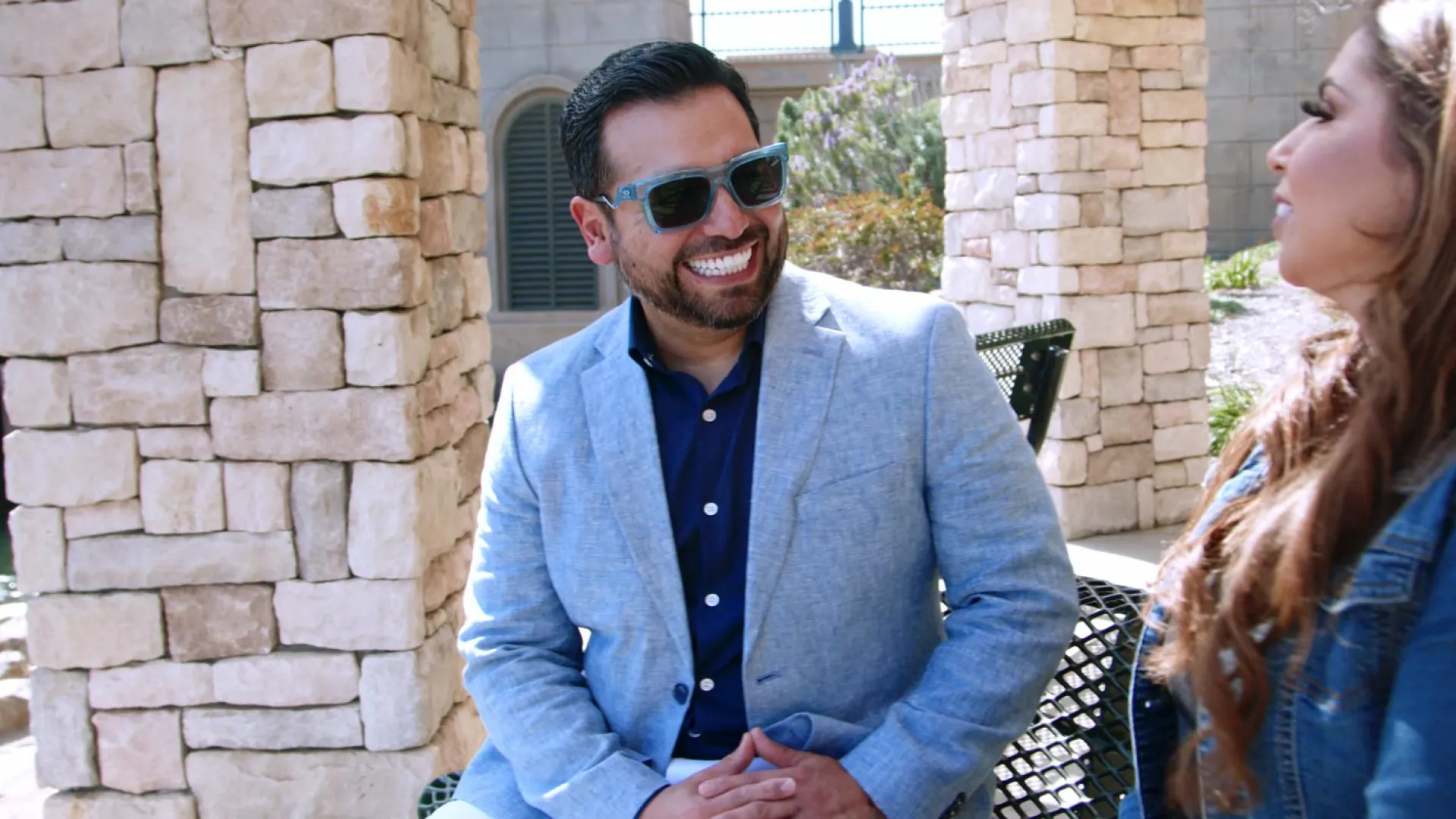 Engaging conversation between two people by a stone structure in an outdoor setting.