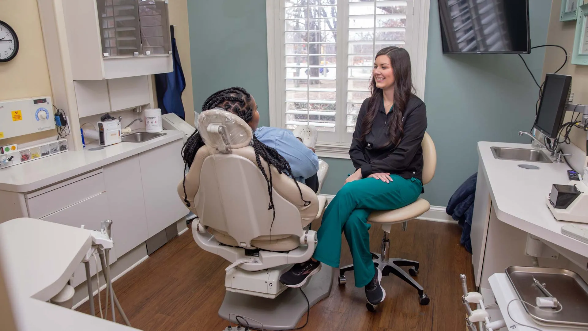 Dentist consulting with patient in a modern dental office with natural light from arched window.