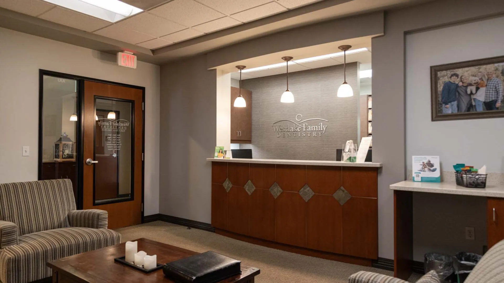 Reception area of Wesdale Family Dentistry with wooden desk, pendant lights, and comfortable seating.