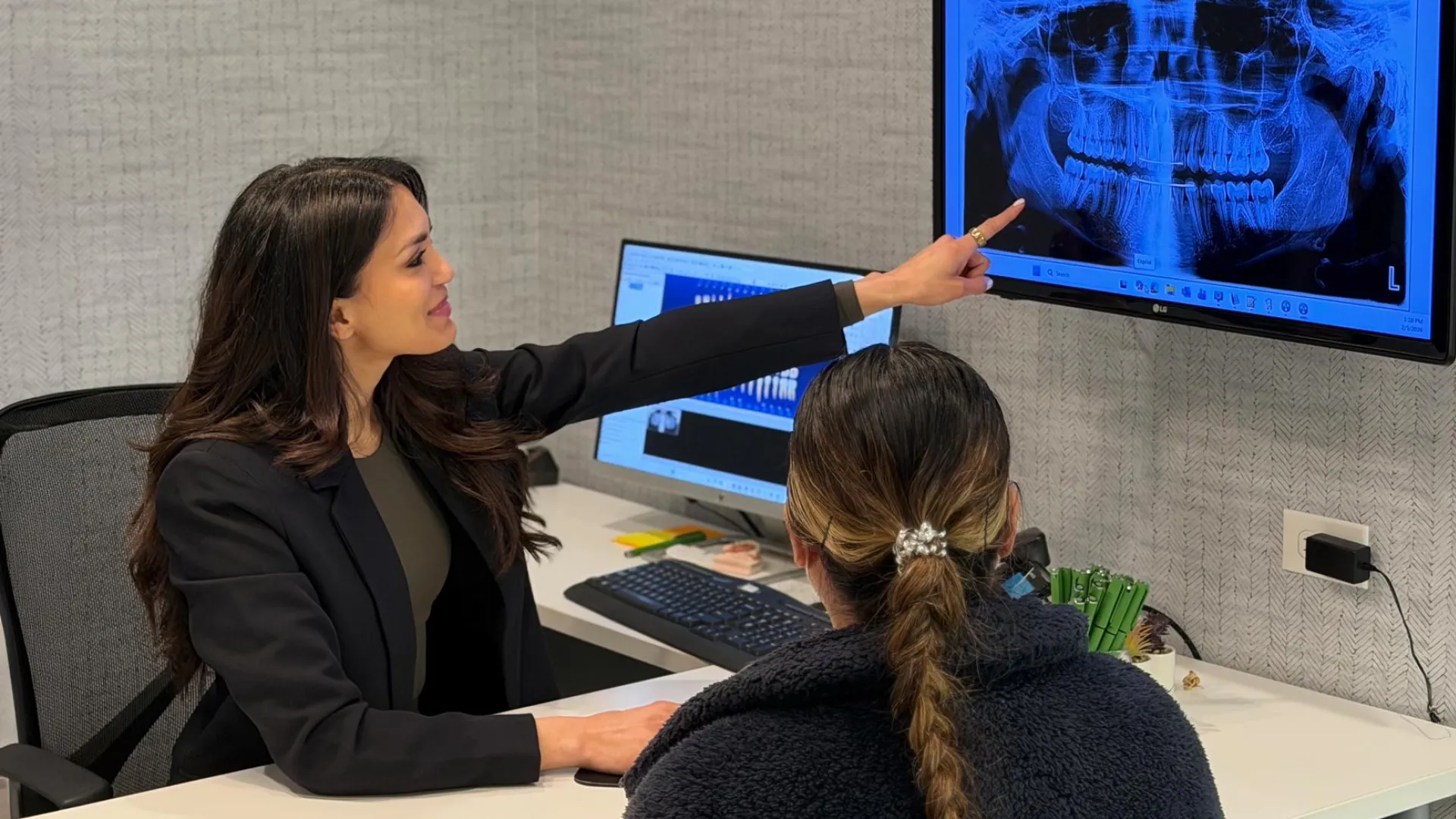 Dentist explaining dental X-ray results to a patient in a modern clinic office setting.