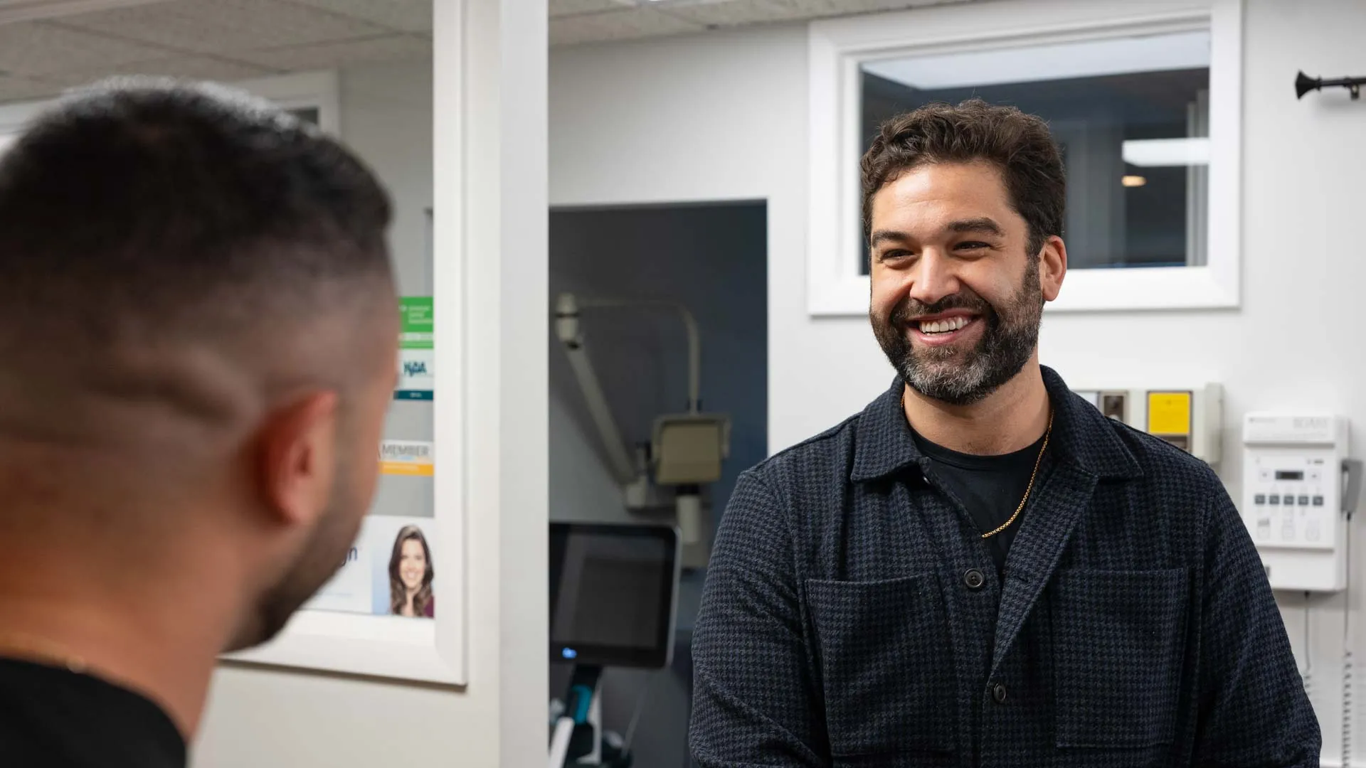 Two men smiling and talking in a modern indoor office setting with computer equipment in the background