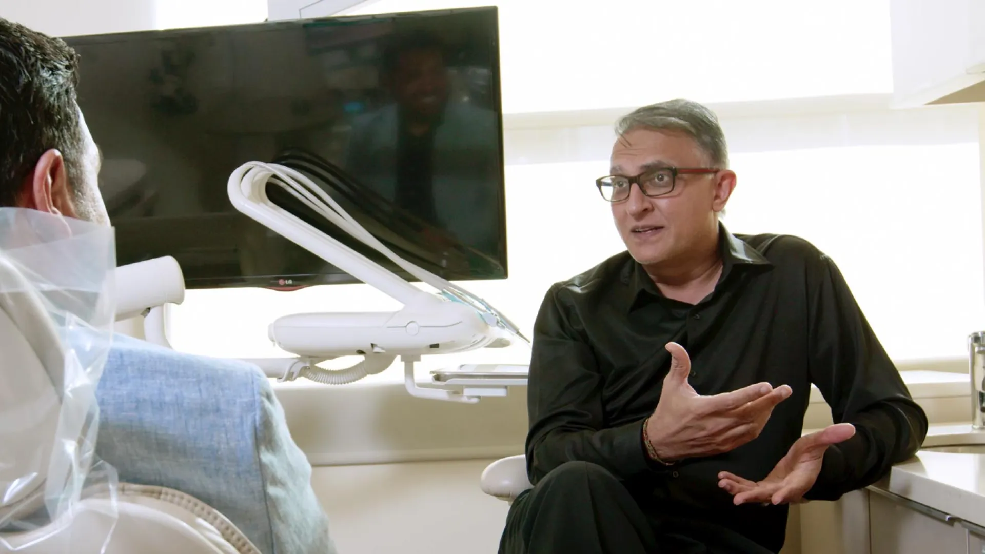 A dentist consults with a patient in a modern dental office, showcasing professional care.