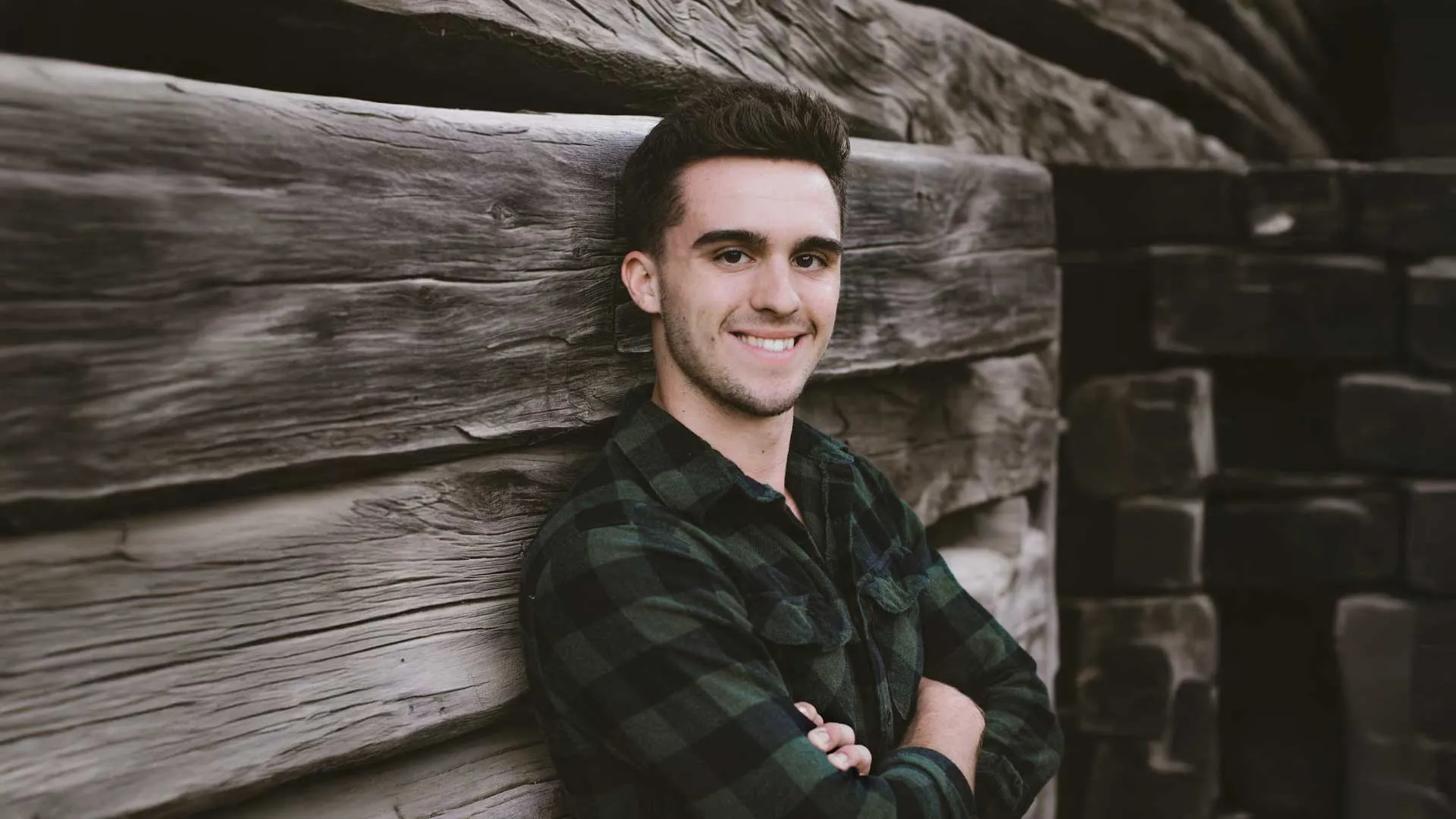 a man standing in front of a brick wall