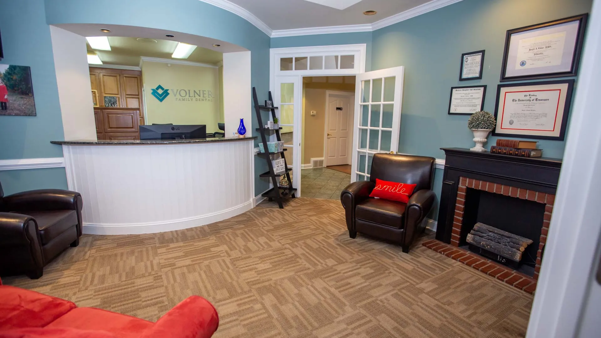 Reception area of Volner Family Dentistry with seating, front desk, certificates, and calming blue walls.
