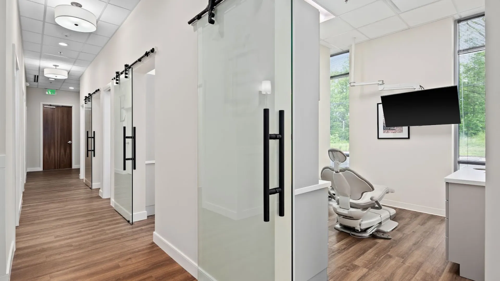 Modern dental office interior with sliding glass doors and wooden flooring.