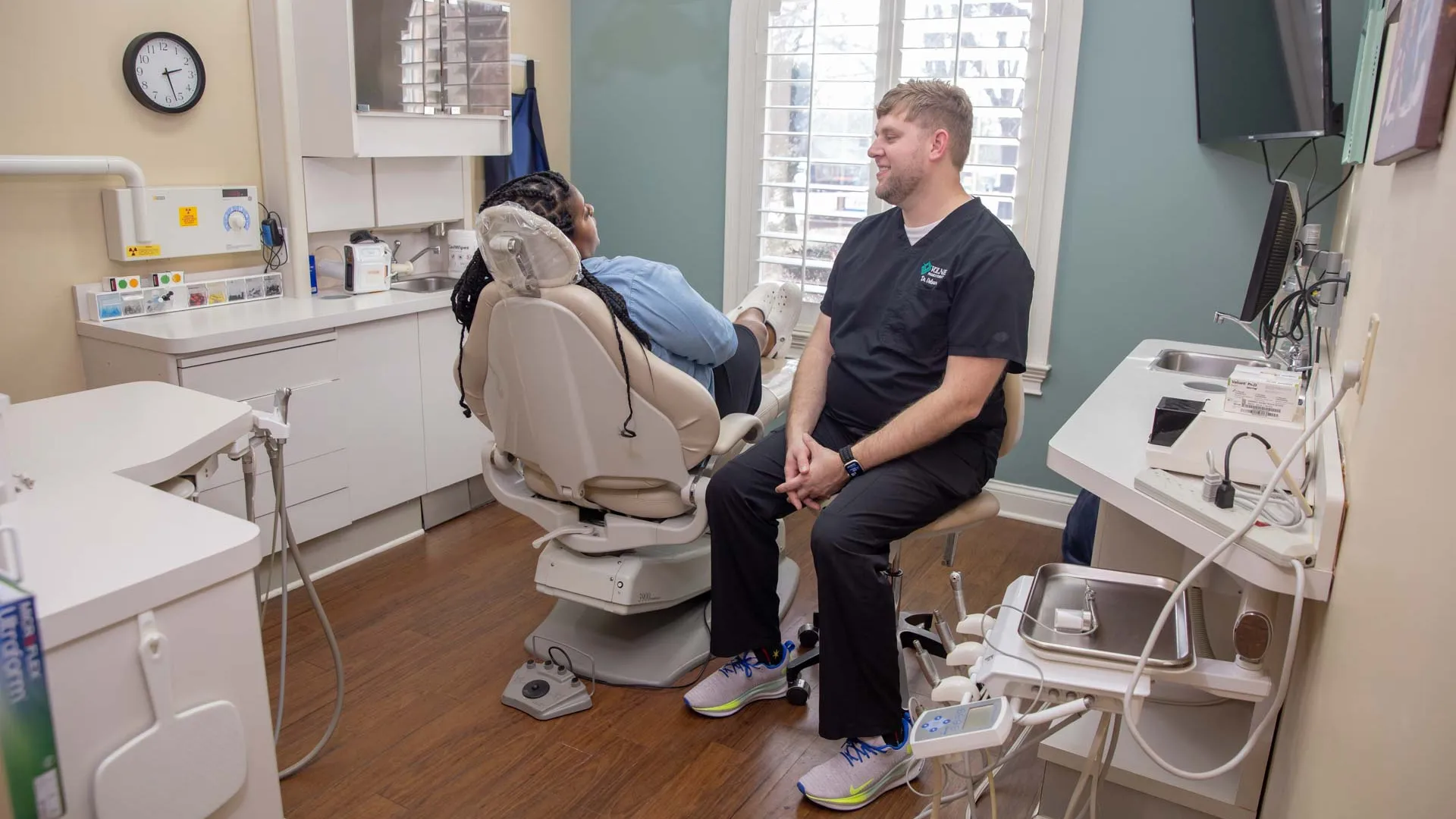 Dentist consulting a patient in a modern dental office with a dental chair and equipment.