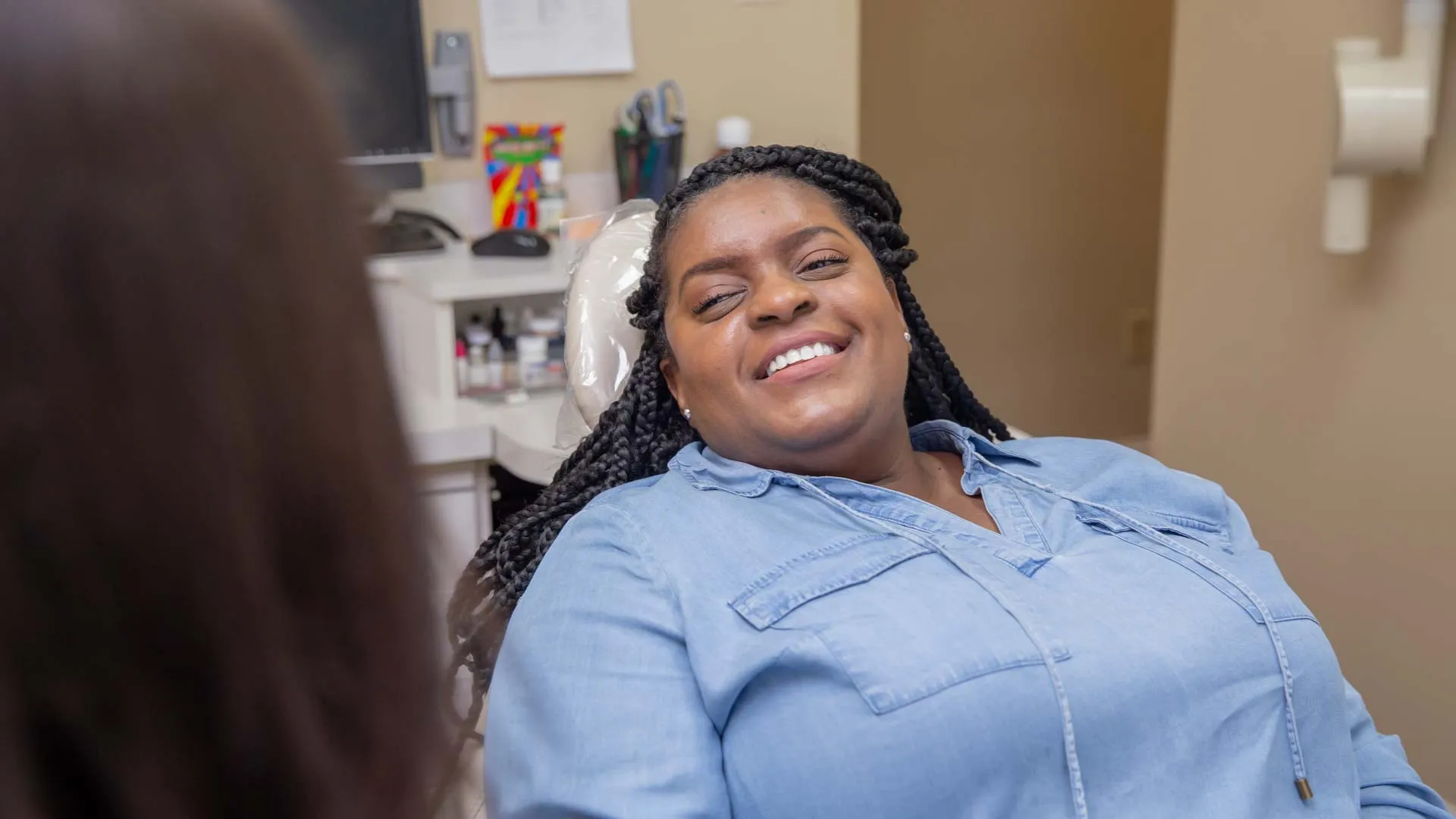 Smiling woman reclining in a dental chair during a relaxed dental visit in a clinic setting.