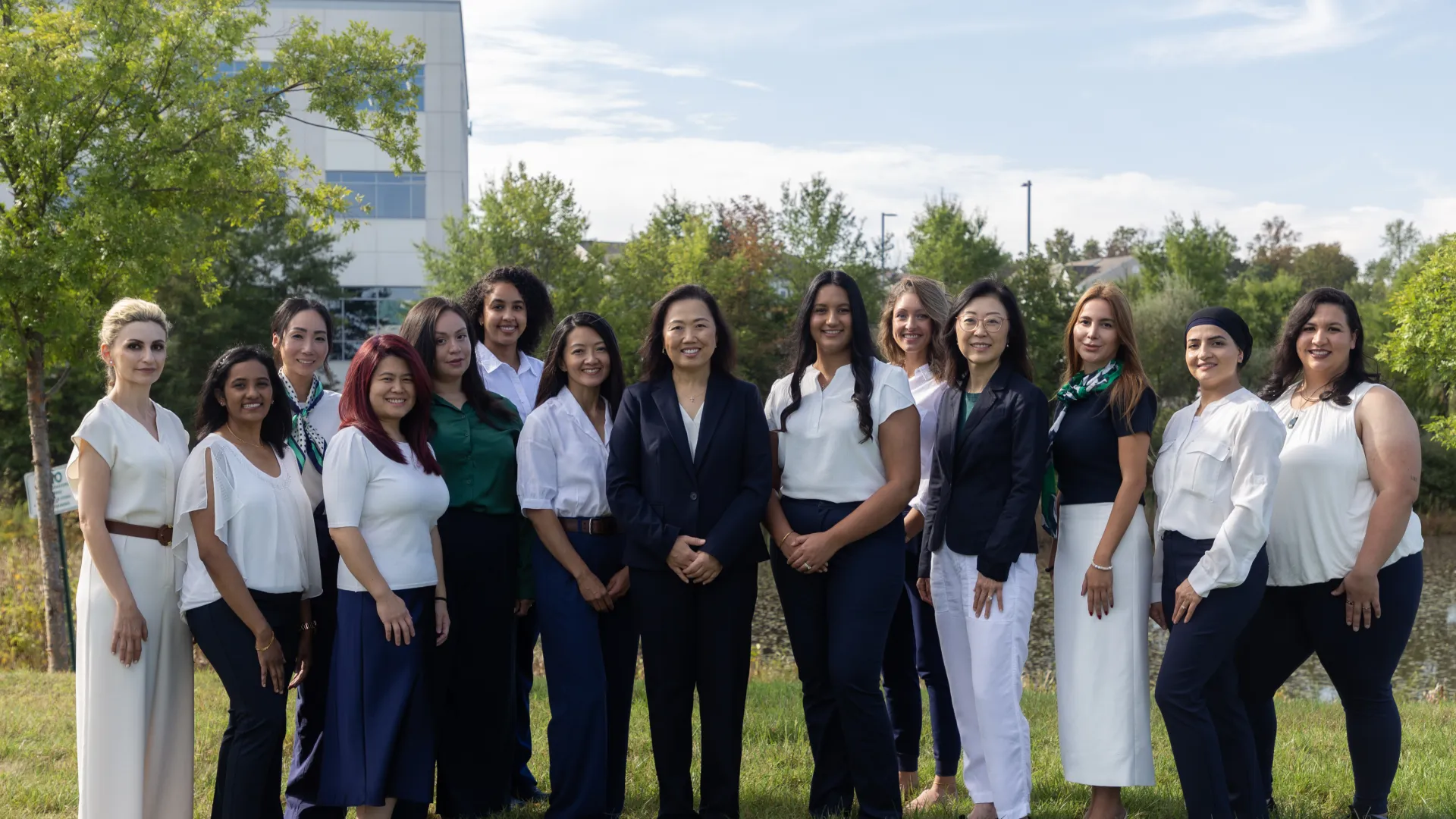 Diverse group of professional women standing outdoors in business casual attire on a sunny day.