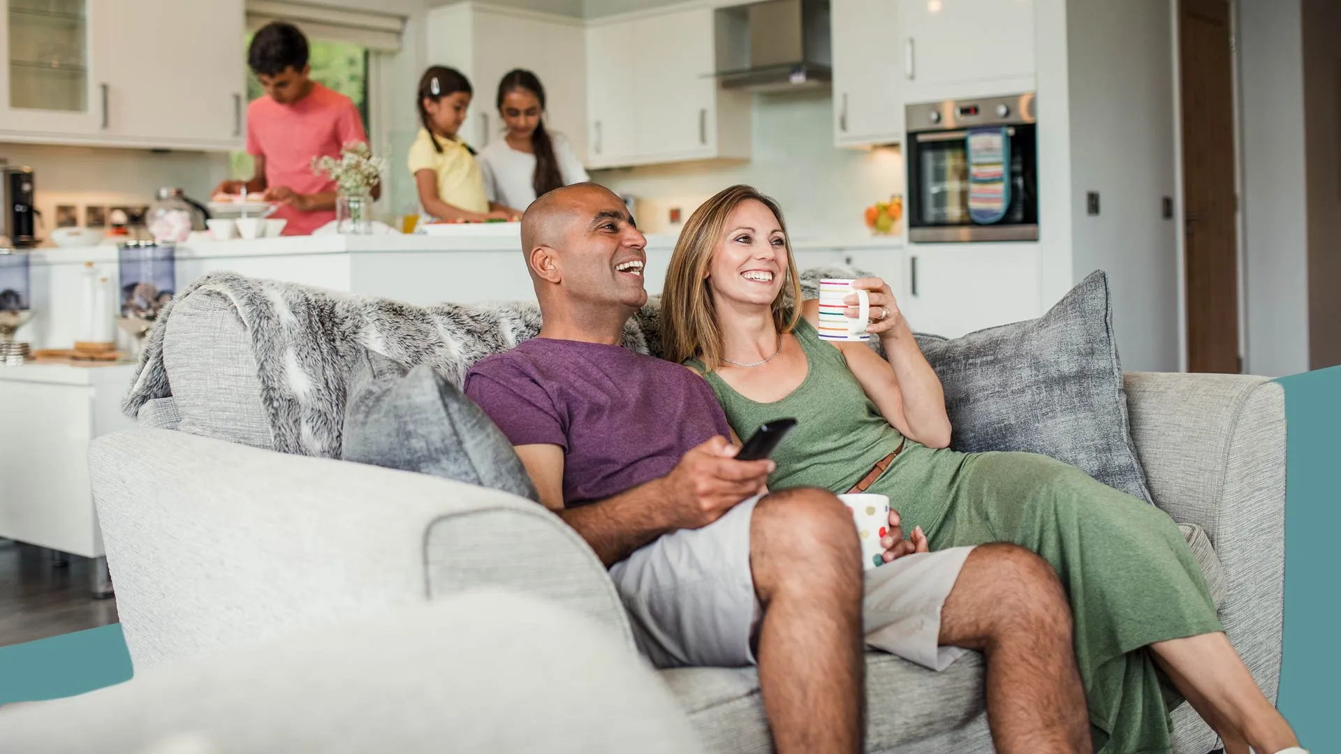 a man and woman sitting on a couch and smiling at the camera