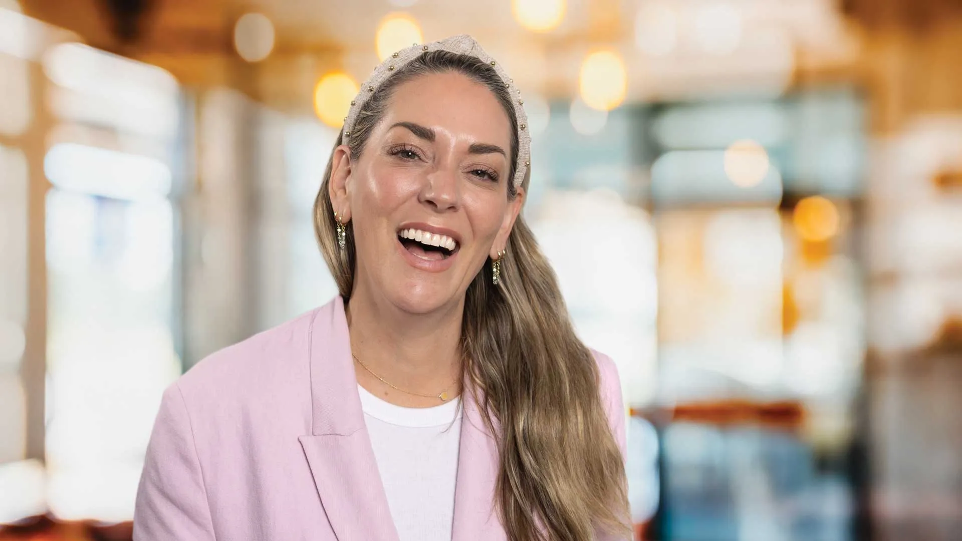 a woman smiling in front of a grey wall