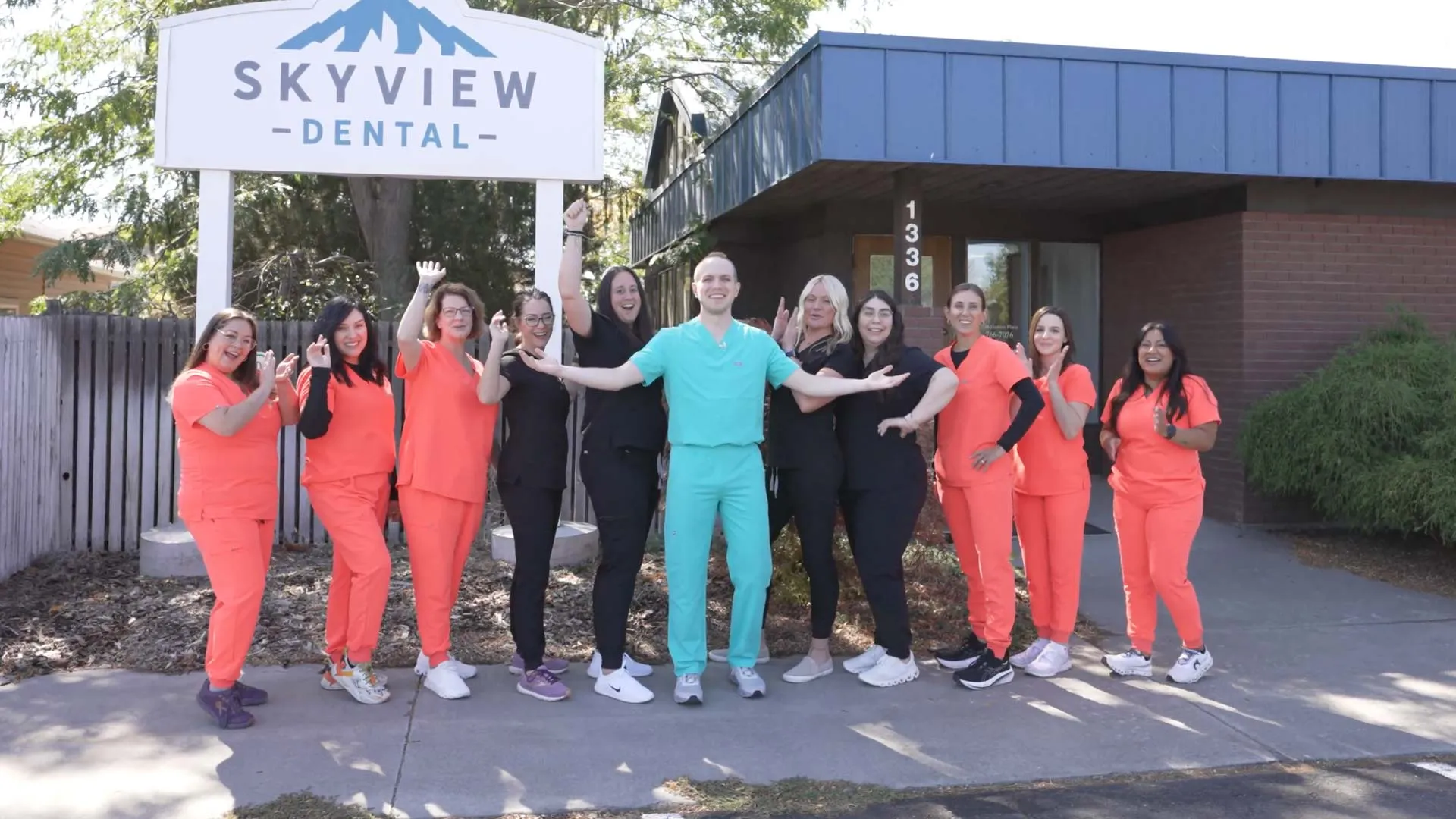 Skyview Dental team posing outside their clinic in colorful scrubs, smiling and welcoming patients.