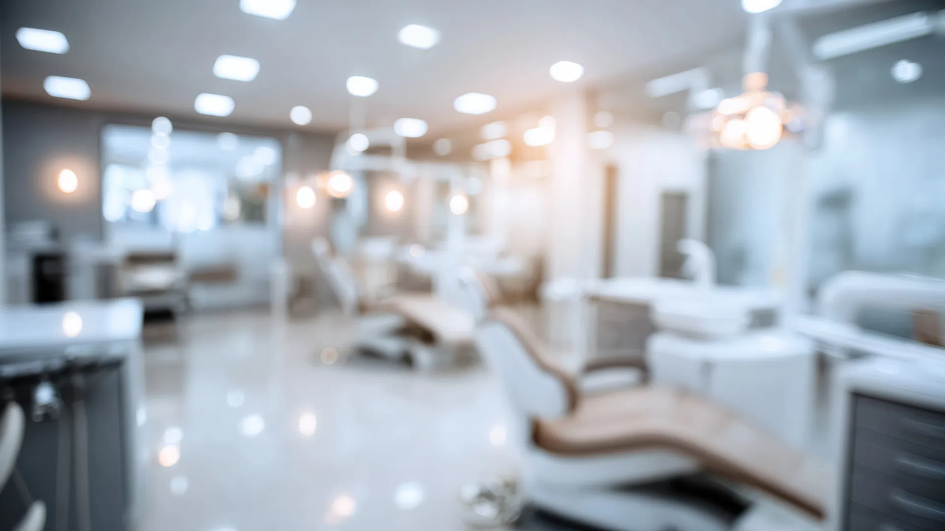 Blurred modern dental clinic interior with dental chairs and bright lighting.