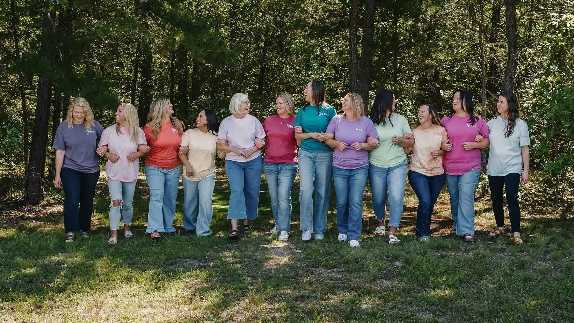 Group of diverse women walking confidently on a paved path surrounded by autumn trees in a park.