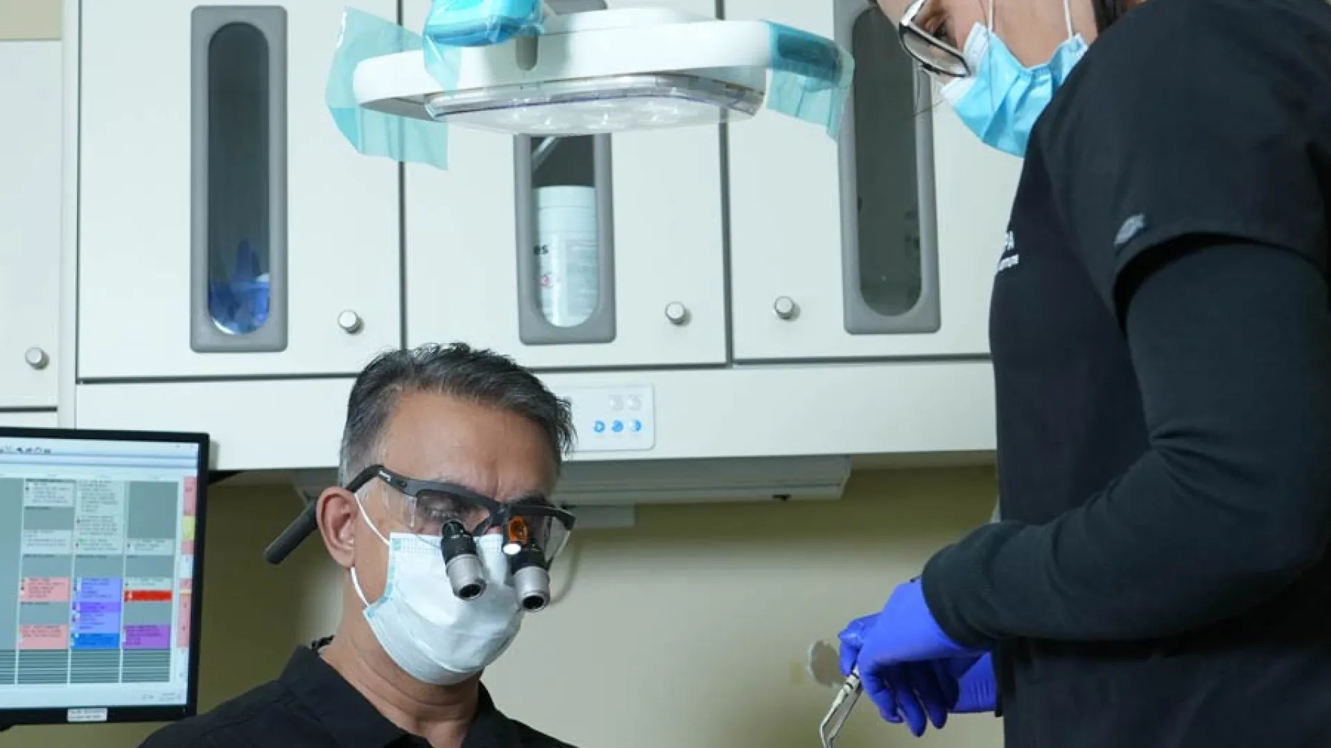 A dentist performing a procedure with an assistant in a modern dental office.