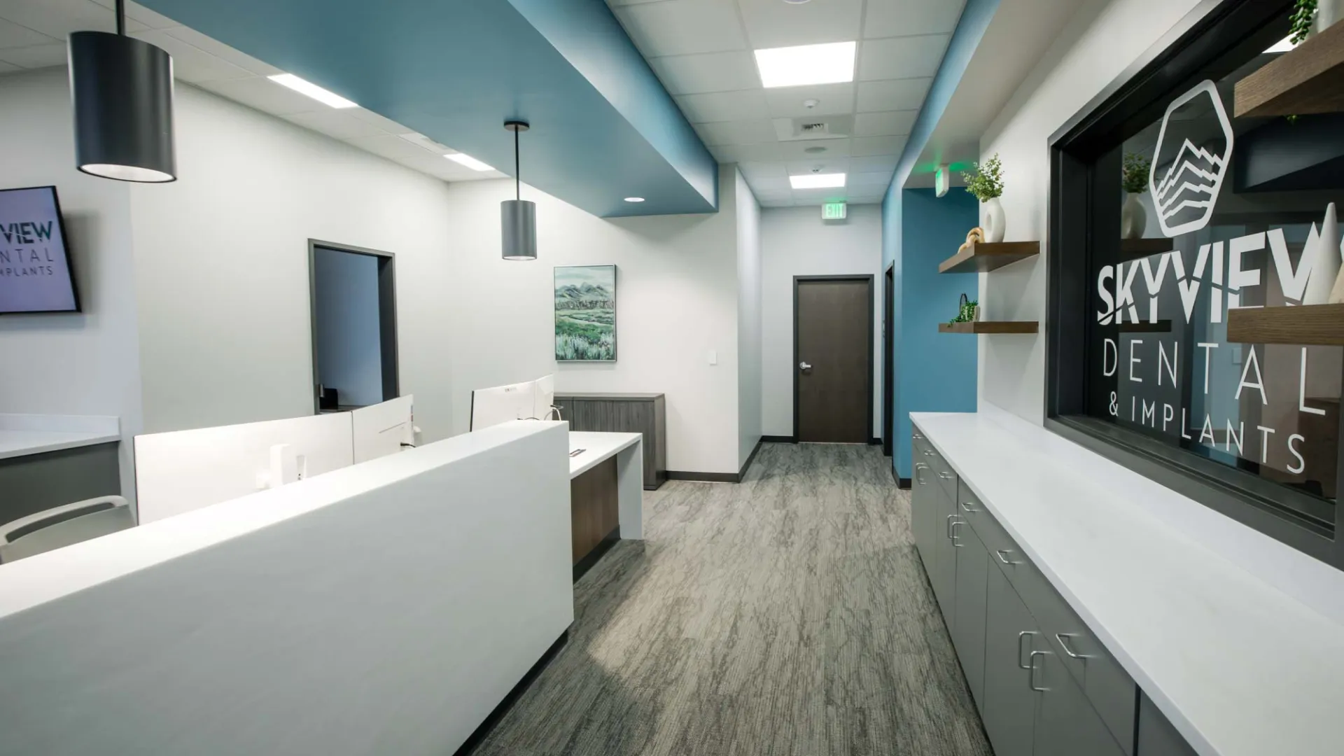 Modern dental office reception area with white desks, blue ceiling accents, and SkyView Dental signage.