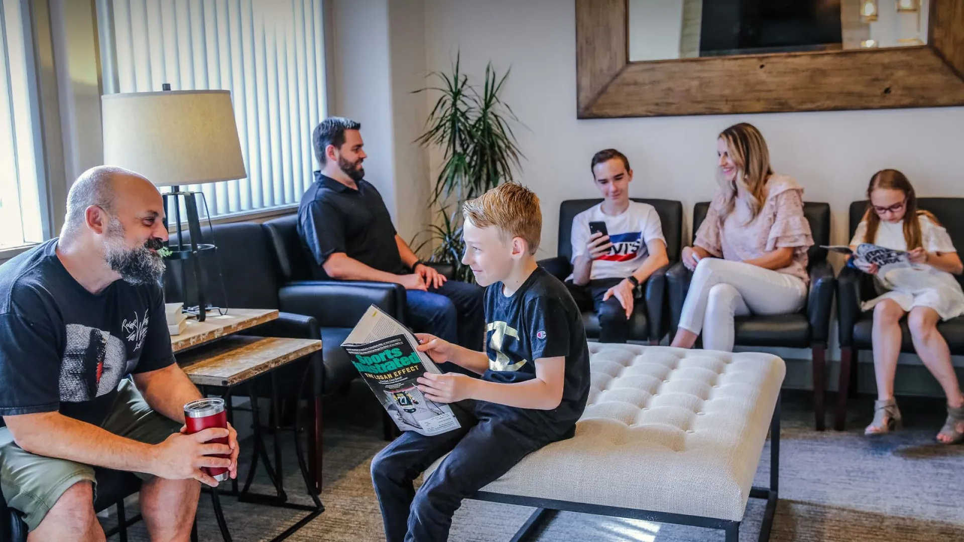 Family enjoying time together in a cozy living room, reading and chatting comfortably.