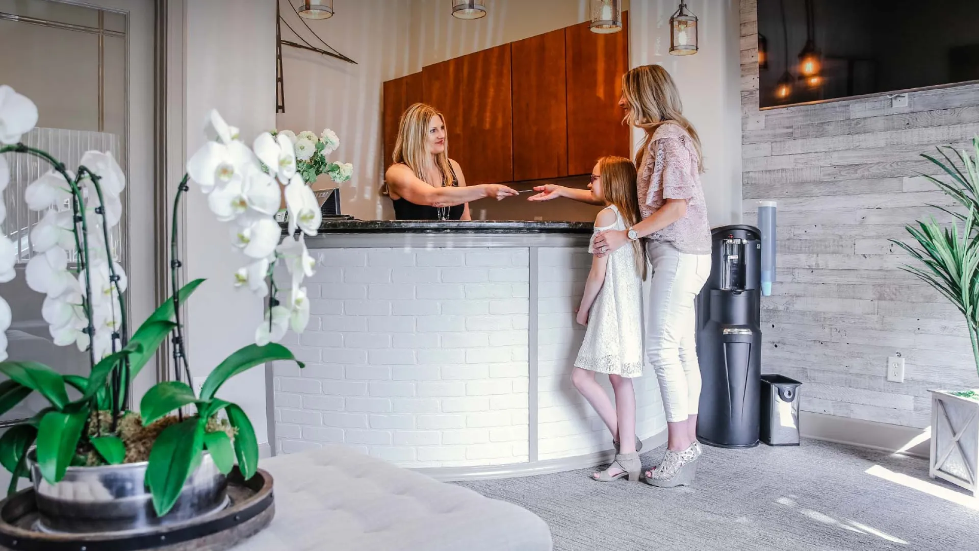 Welcoming reception area with stylish decor, a receptionist, and a mother with her daughter.