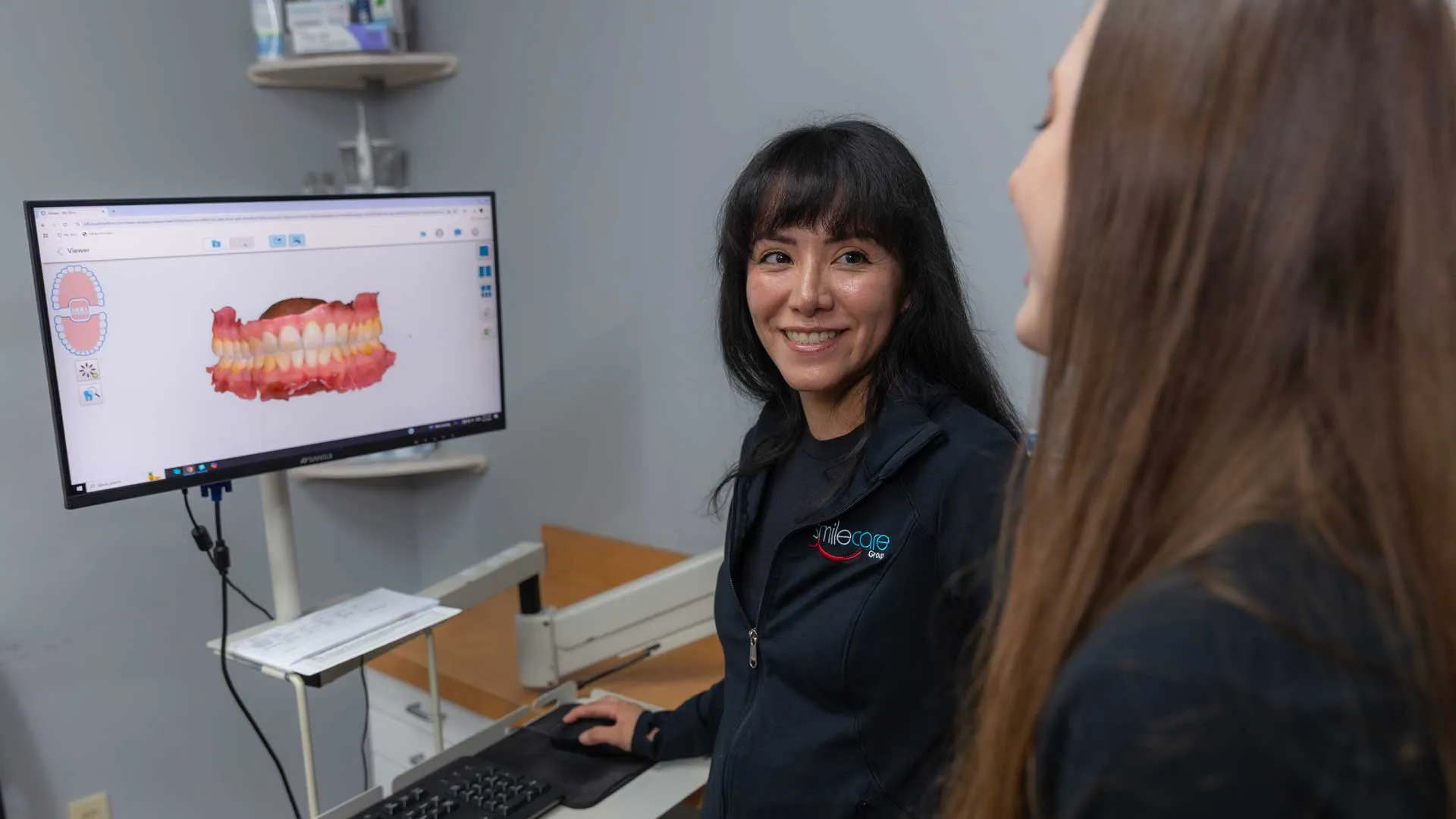 Dentist explaining 3D dental scan on monitor to patient in modern dental office.