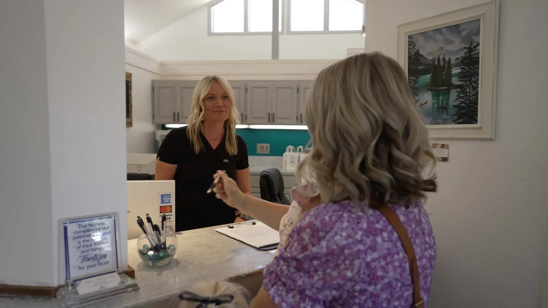 Woman at reception desk handing over keys to a female receptionist in a modern office setting