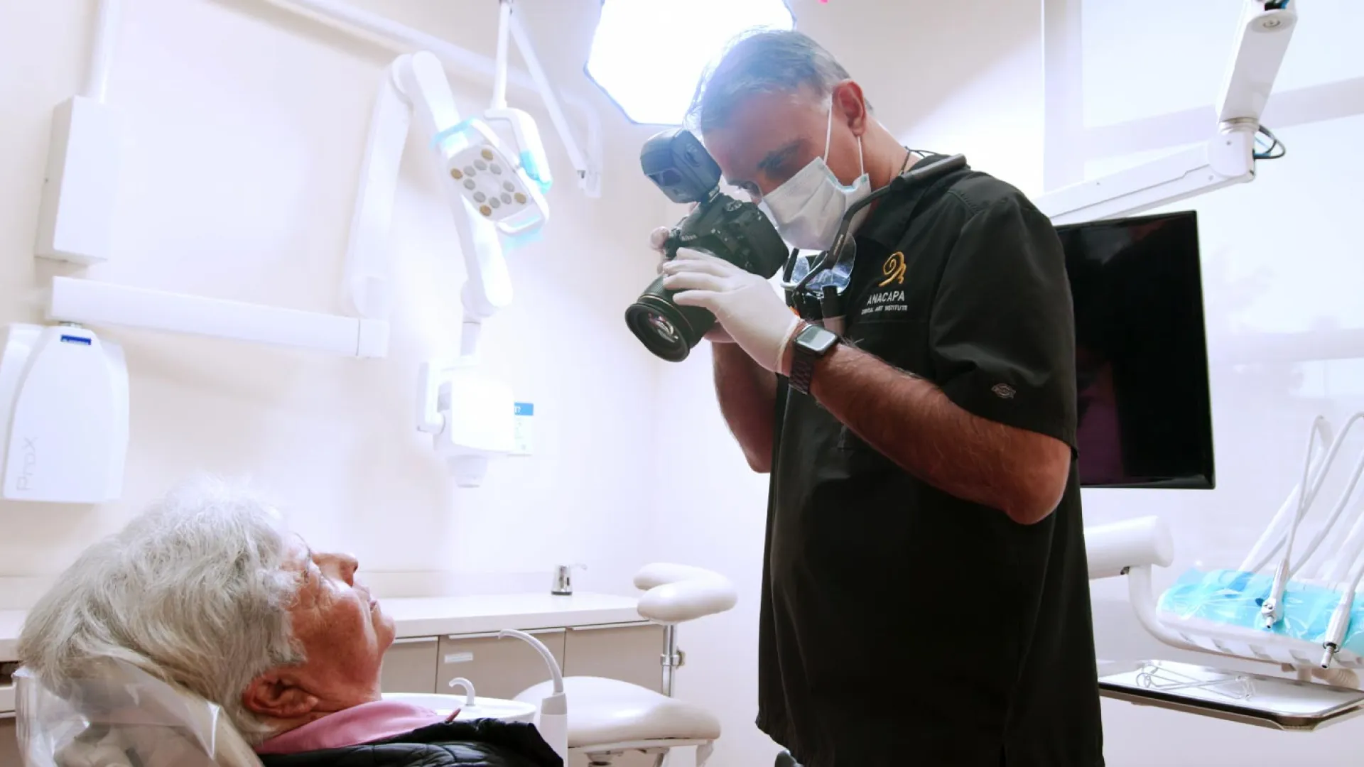 Dentist taking photos of an elderly patient in a modern dental office setting.
