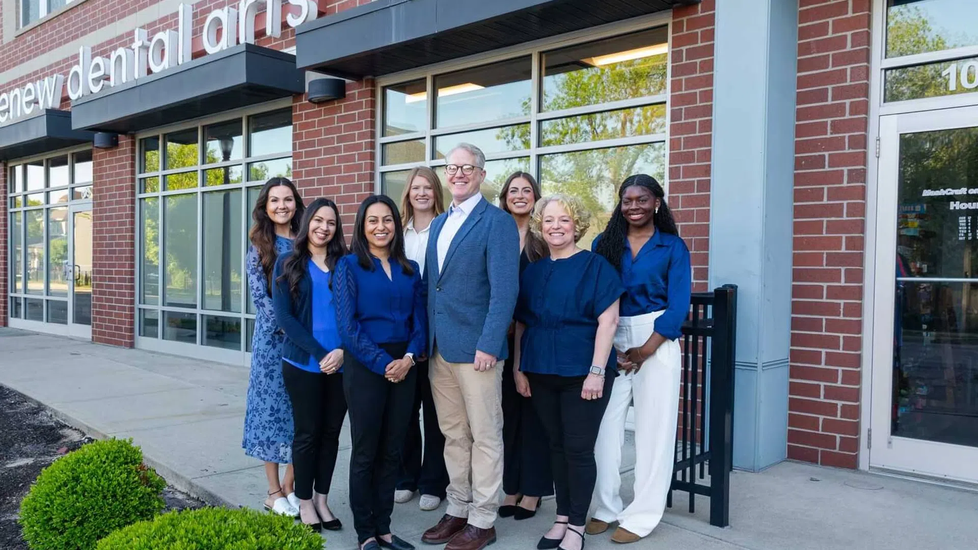 Group of dental professionals standing outside Renew Dental Arts office smiling at camera