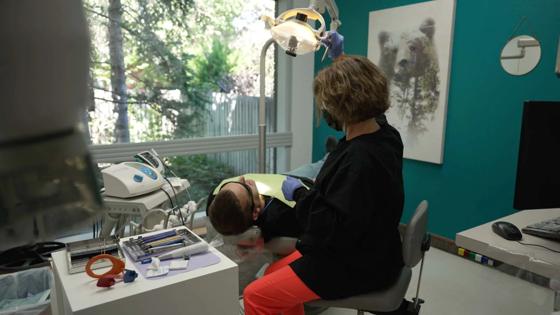 Dentist examining patient in a bright dental office with natural light and dental equipment nearby