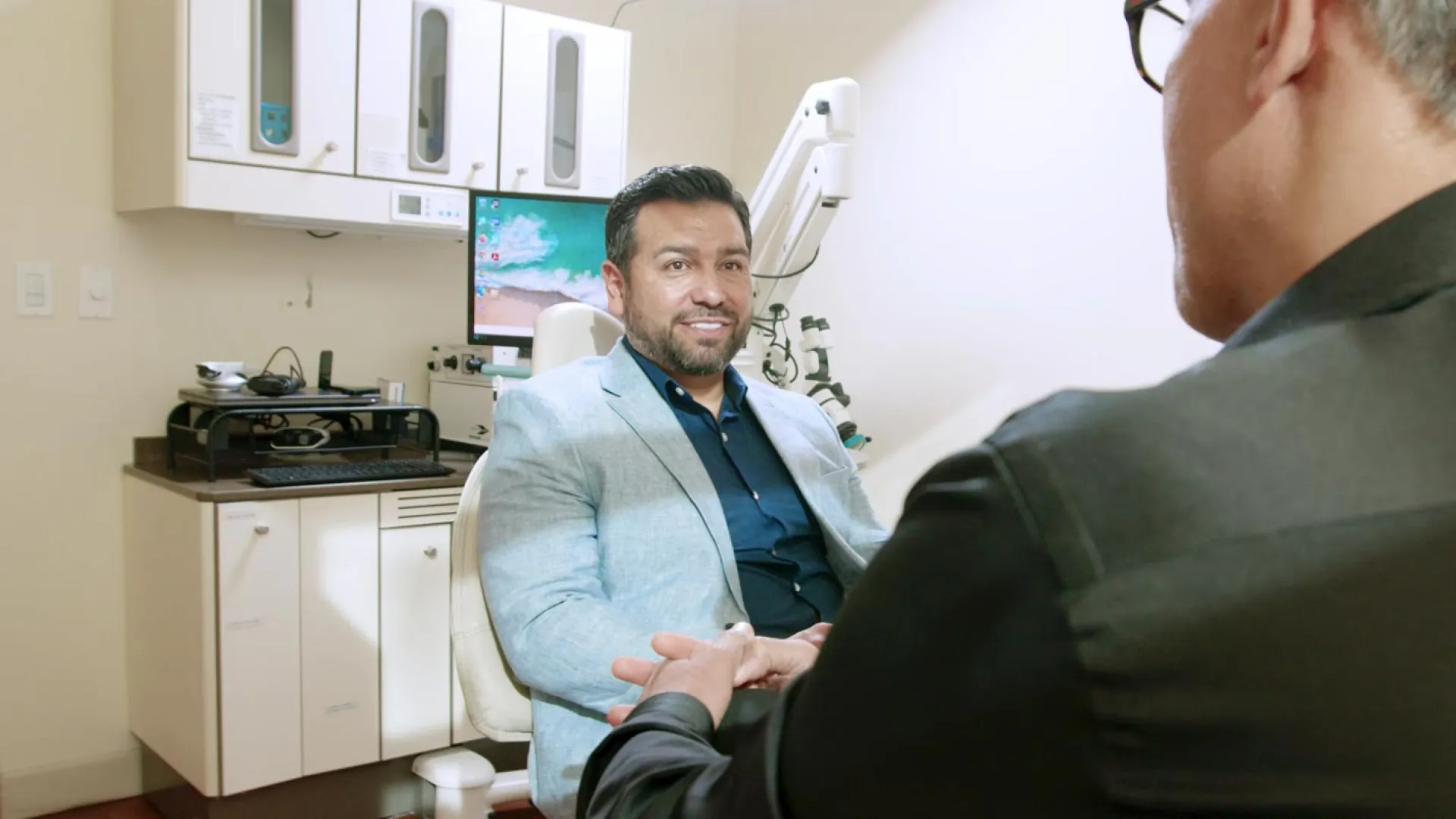 A smiling patient in a dental clinic engages with a dentist during a consultation.