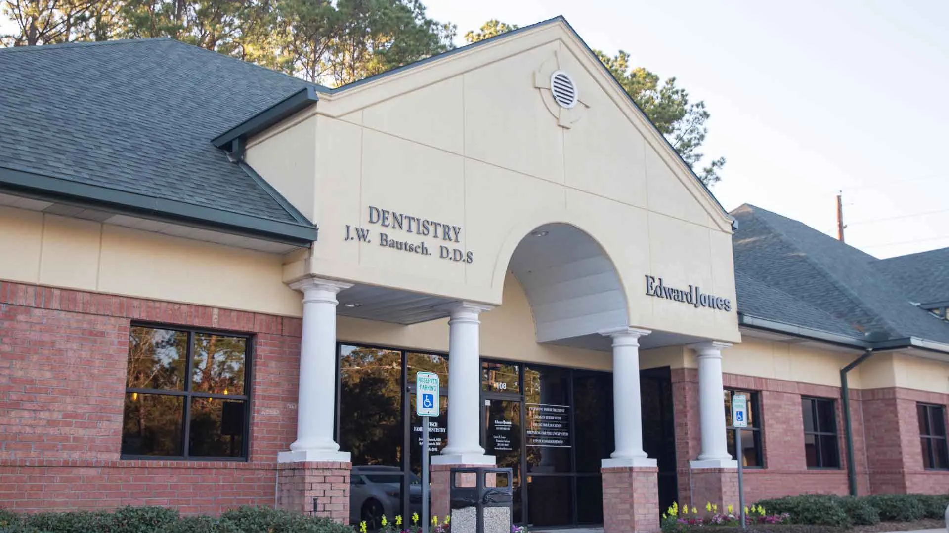 Exterior of a brick and beige dental office and Edward Jones building with columns and large windows.