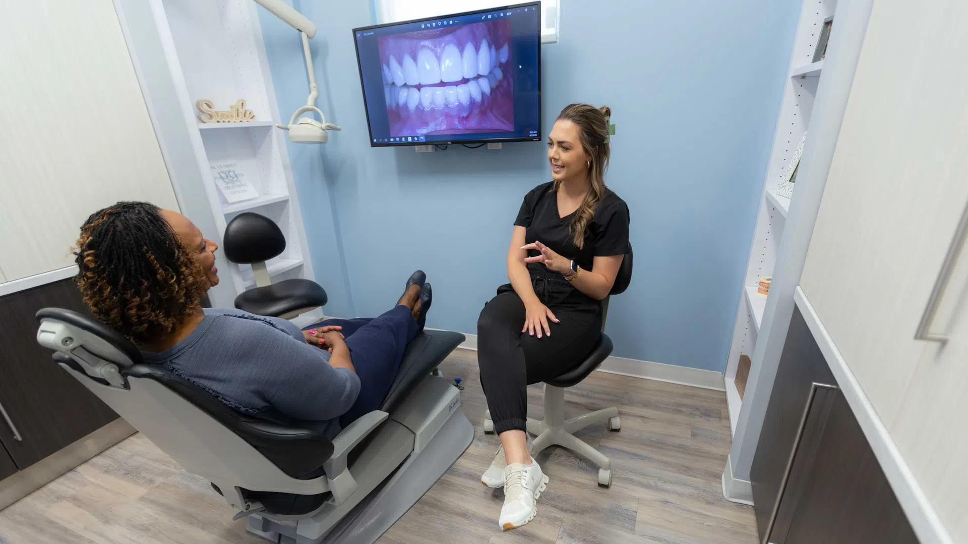 Dentist consulting patient with dental X-ray image displayed on monitor in a modern clinic room