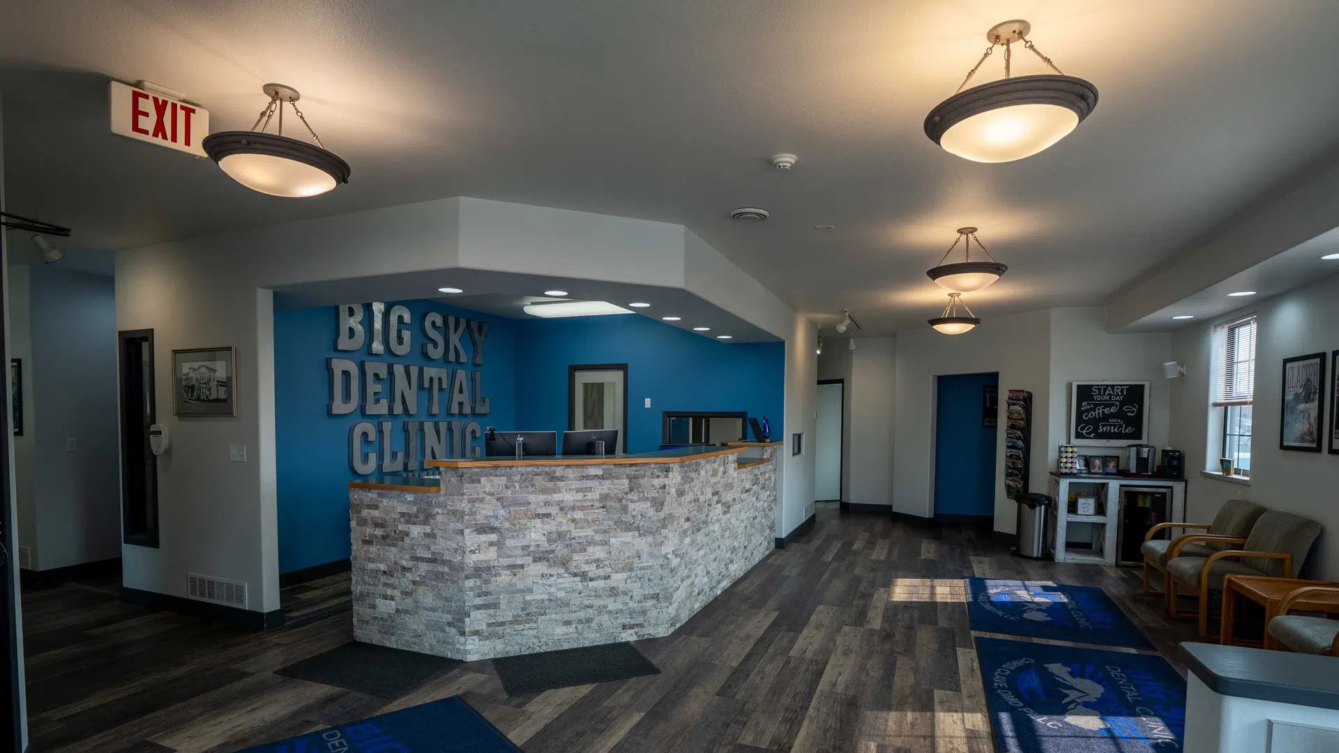 Modern dental clinic lobby with reception desk, seating area, and wooden flooring under warm lighting.