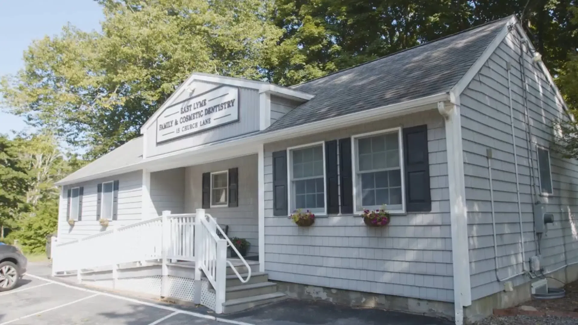 Small white dental office building with stairs, flower boxes, and signage for East Lyme Family & Cosmetic Dentistry.