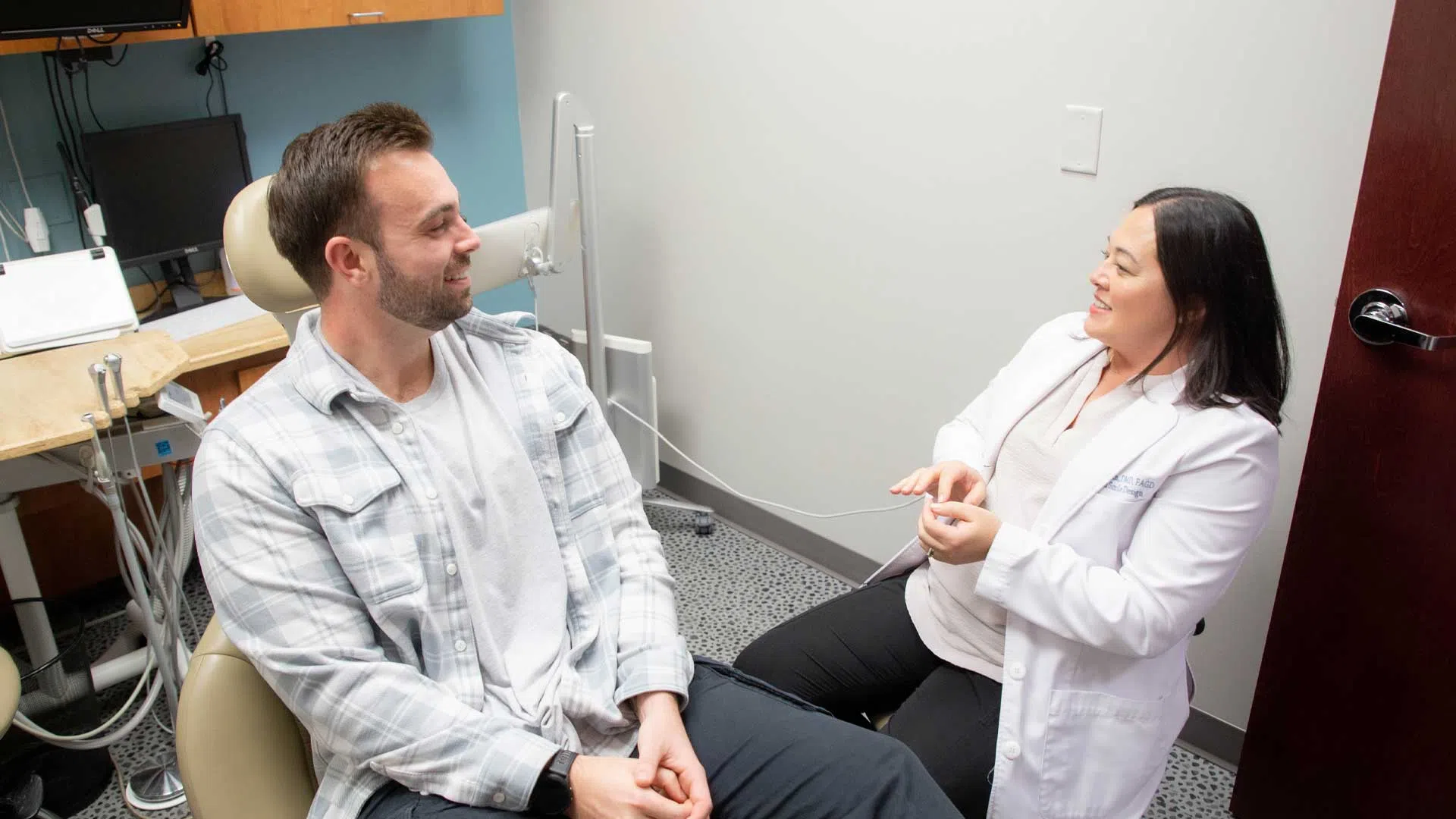 Male patient and female doctor in white coat having a friendly conversation in a medical office.