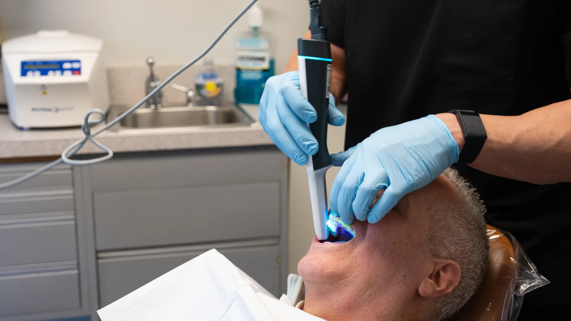 Dentist using digital scanner inside mouth of male patient for dental imaging in clinic.