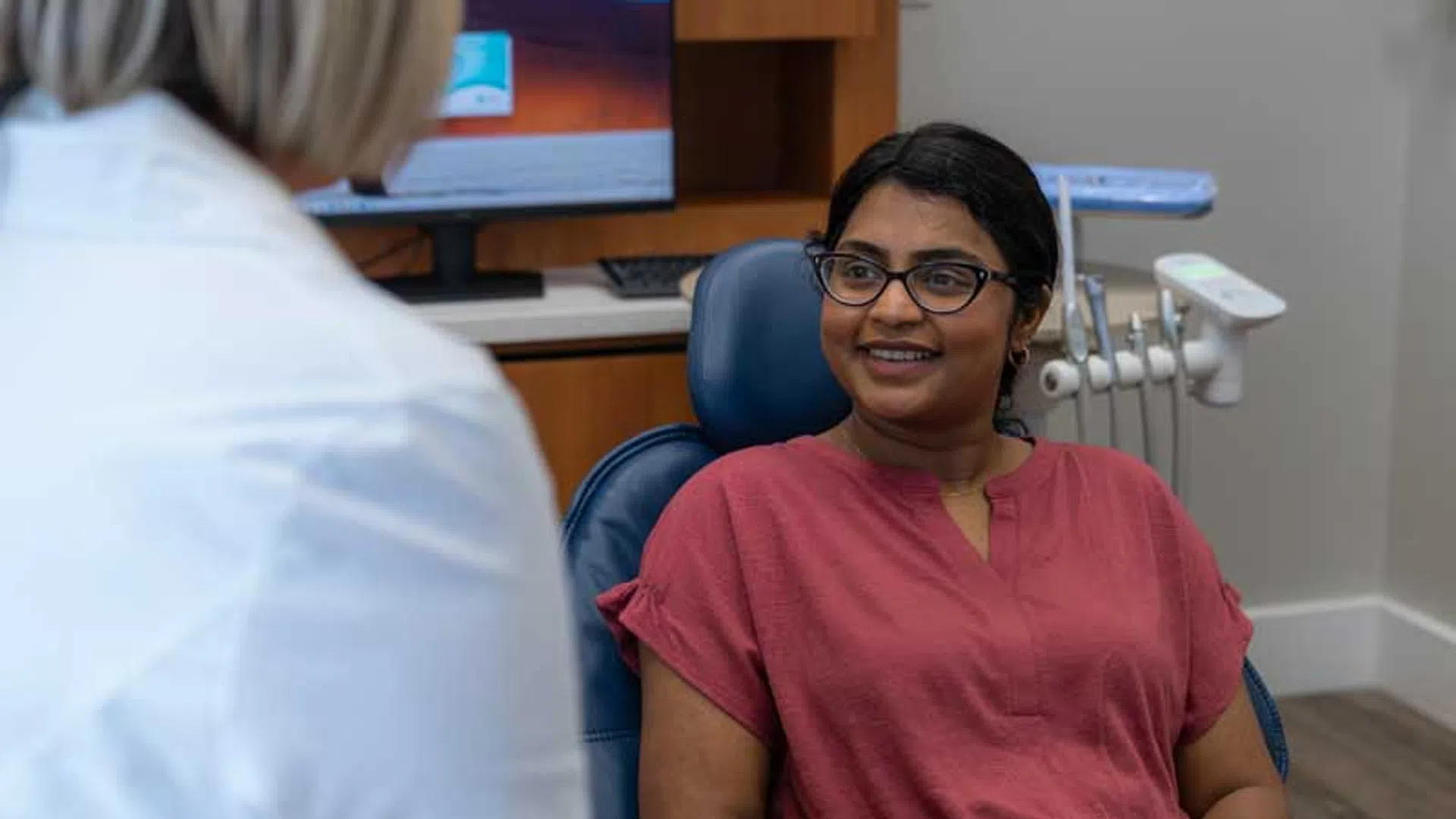 Patient smiling and talking with a dentist in a dental office during a consultation.
