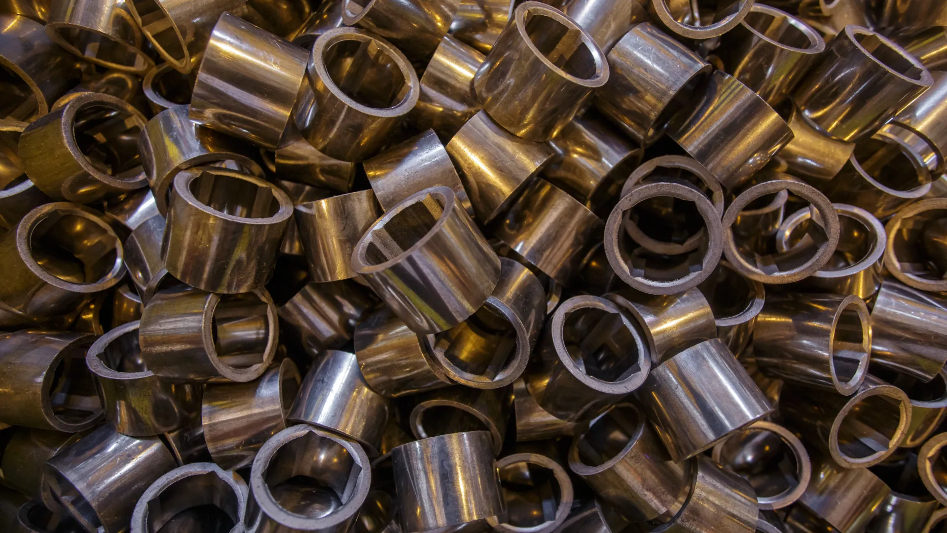 Close-up of stacked metallic cylindrical components with hollow centers and reflective surfaces.