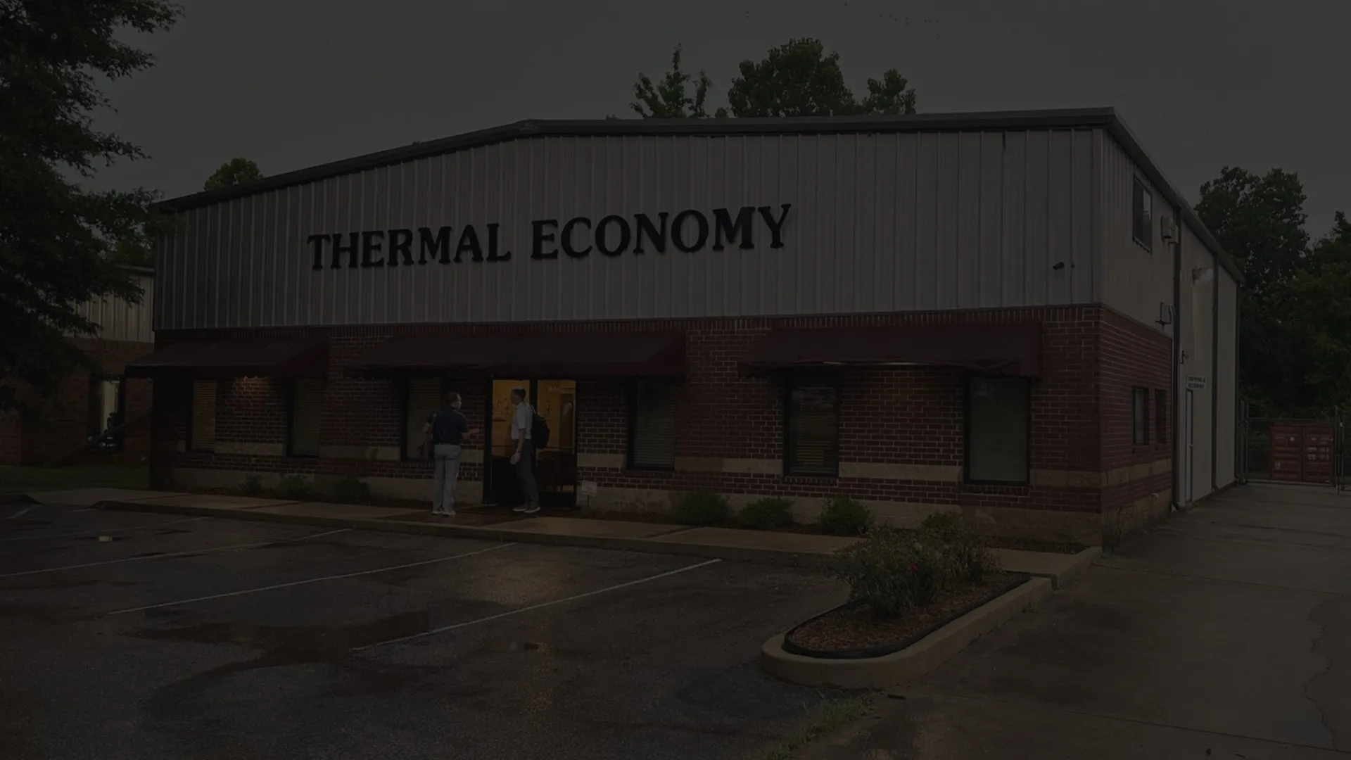 Night view of Thermal Economy company building with empty parking lot.