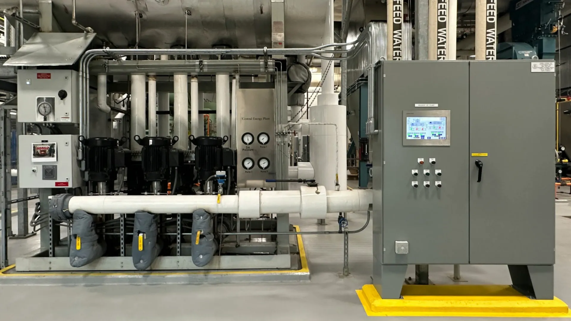 Industrial machinery setup with pipes, gauges, motors, and control panel in a clean factory environment