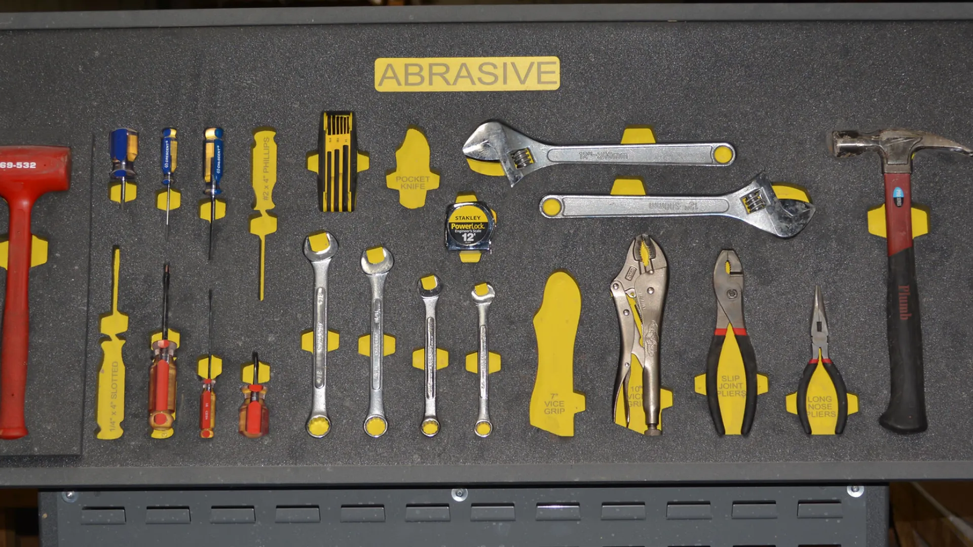 Organized toolbox drawer with labeled hand tools including screwdrivers, wrenches, pliers, hammer, and measuring tape.