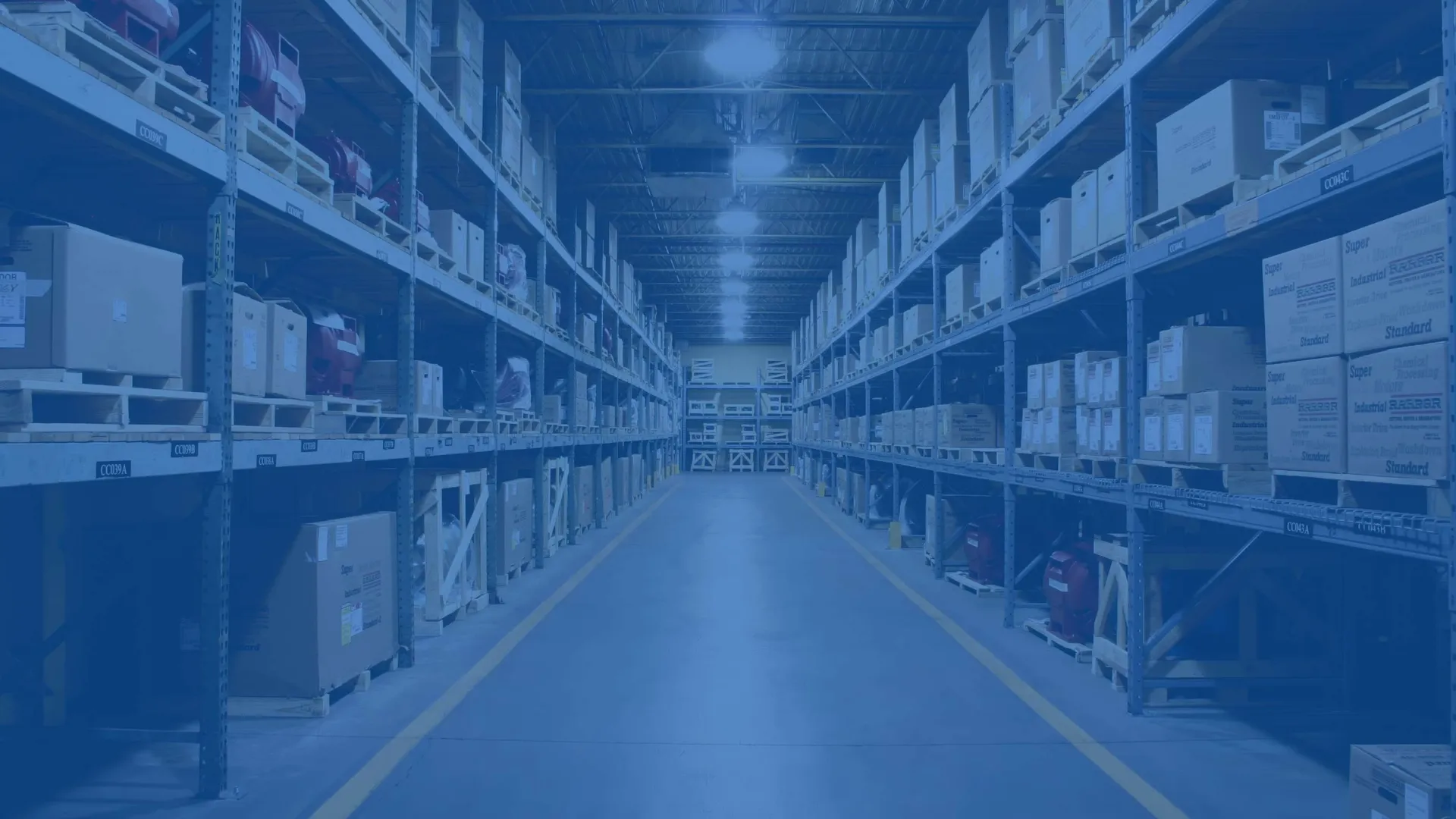 Wide aisle in a large warehouse with tall metal shelves stocked with boxes and packages under bright lighting