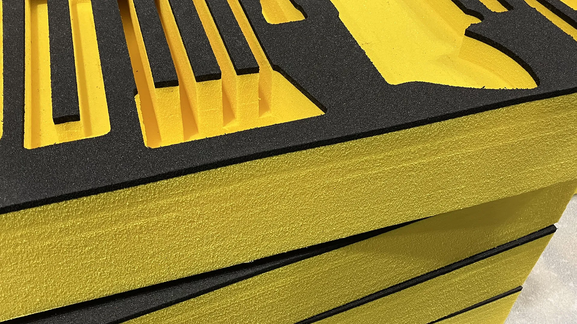 Close-up of black and yellow foam tool organizer with multiple tool-shaped cutouts stacked on a table.