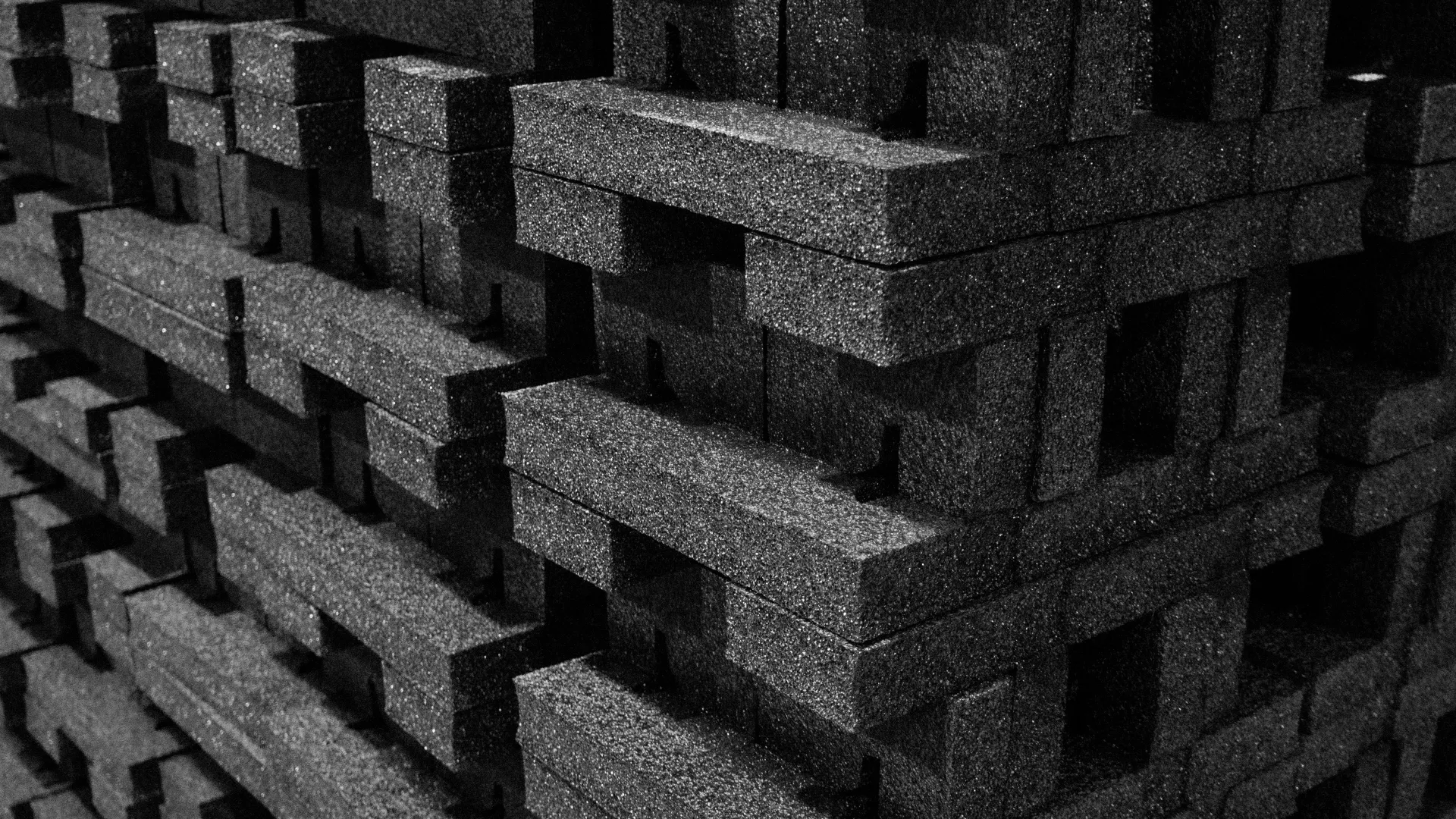 Close-up of stacked black foam blocks with textured surfaces creating a geometric pattern.