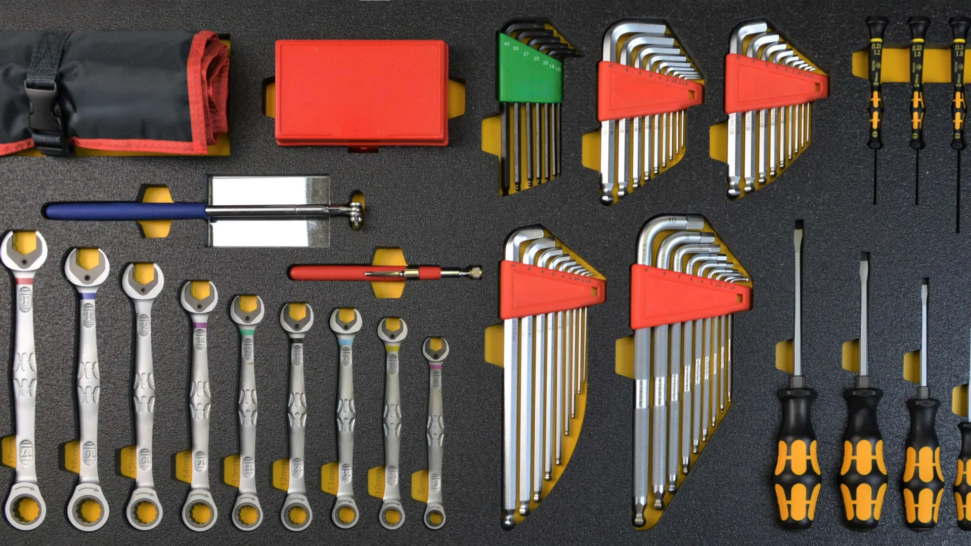 Organized set of wrenches, screwdrivers, and hex keys neatly arranged on a black foam tool organizer.