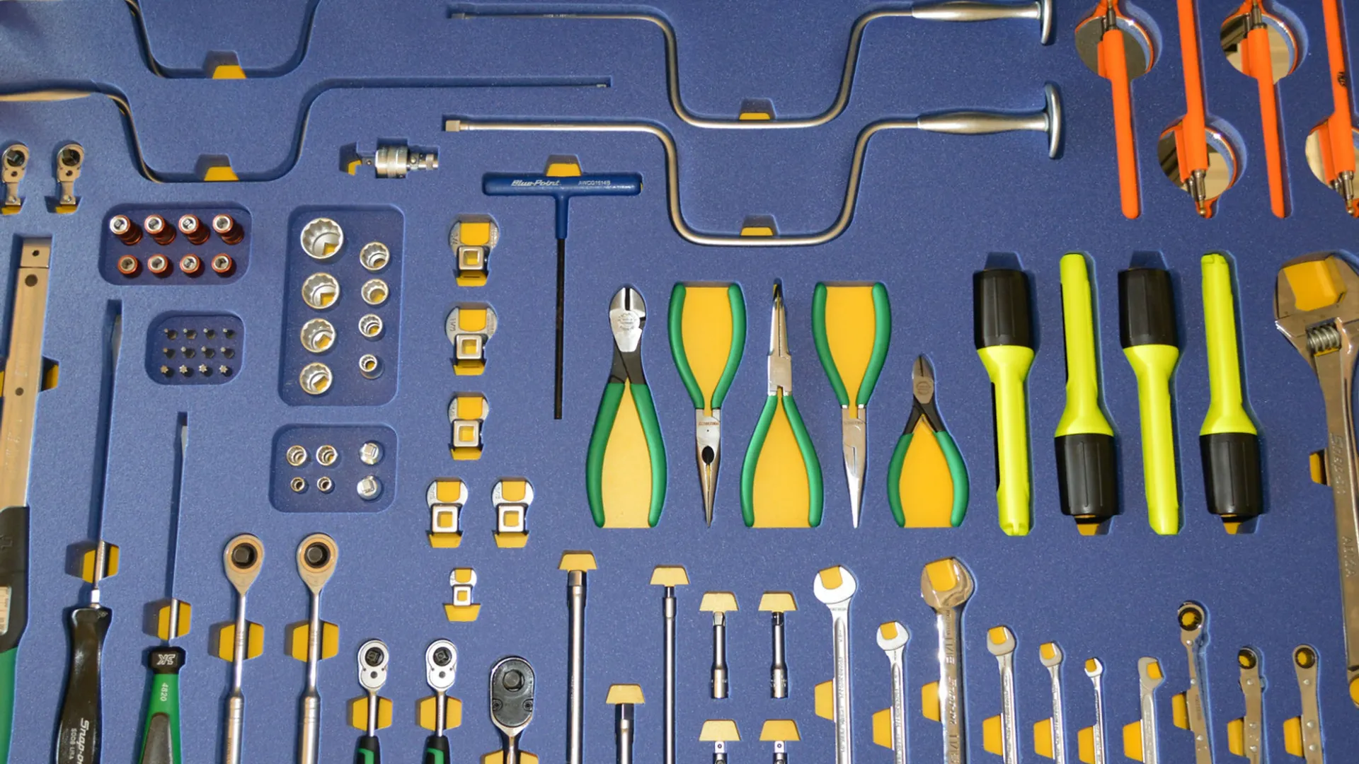 Organized toolkit with pliers, wrenches, screwdrivers, and ratchets on a blue foam insert in a black case.