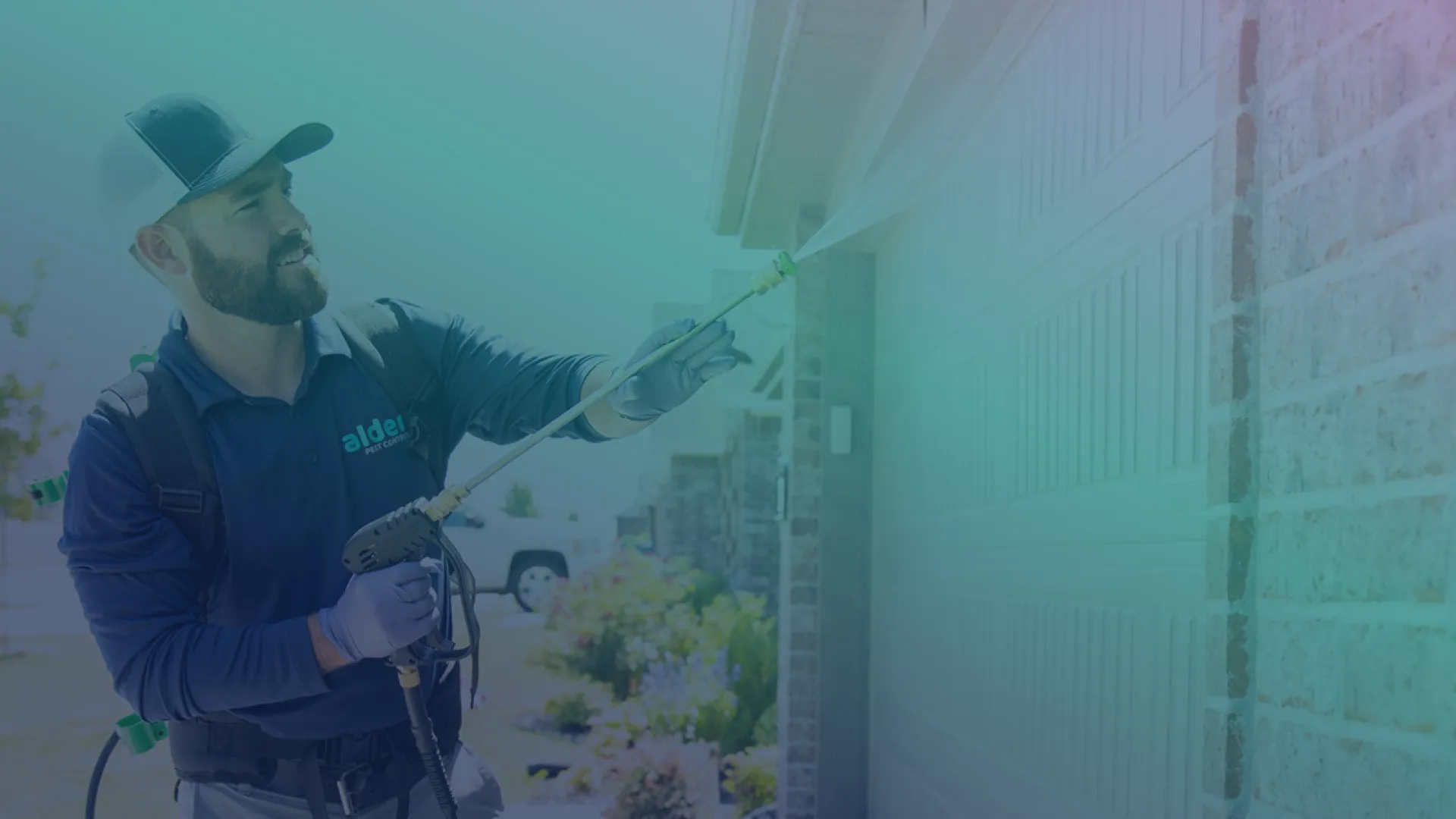A technician sprays pest control solution on a home’s exterior wall, ensuring pest prevention.