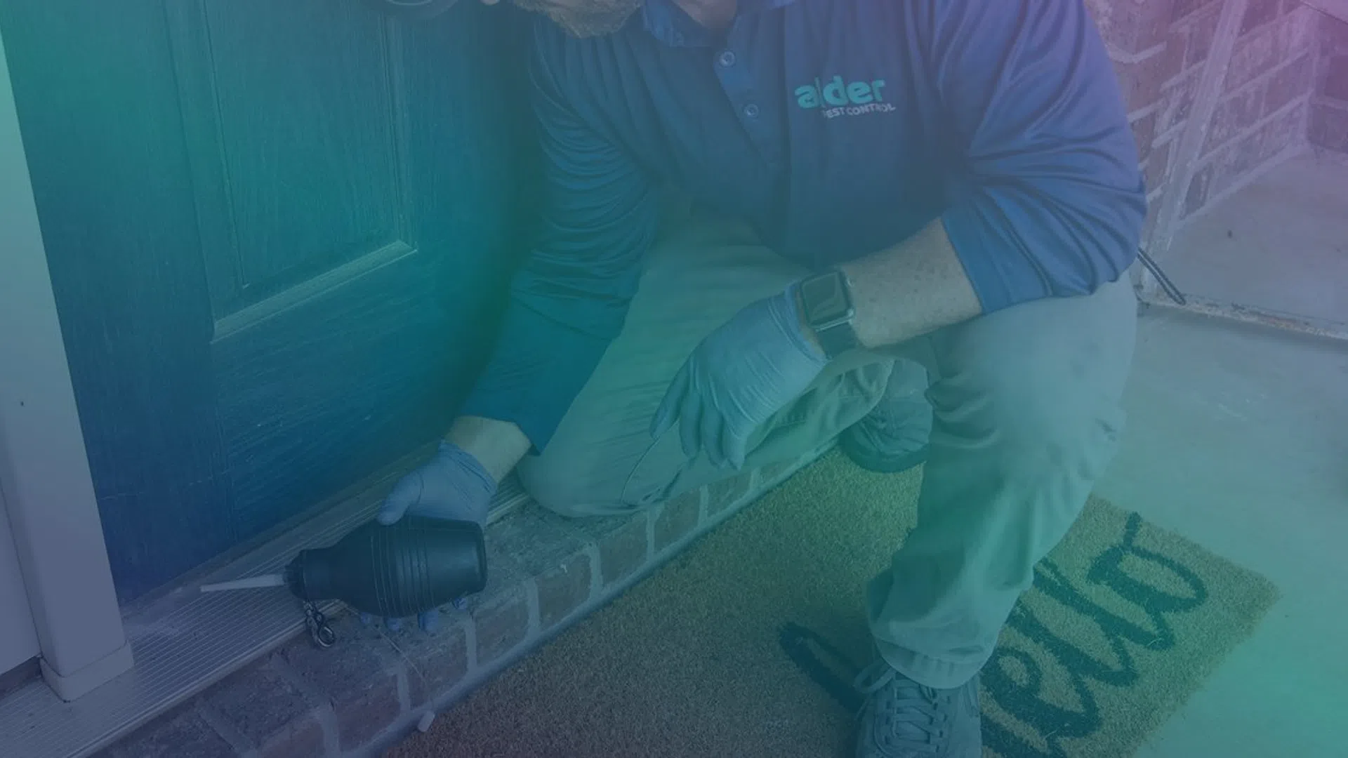 Technician in gloves inspecting a door frame for pests with a tool on a home porch.