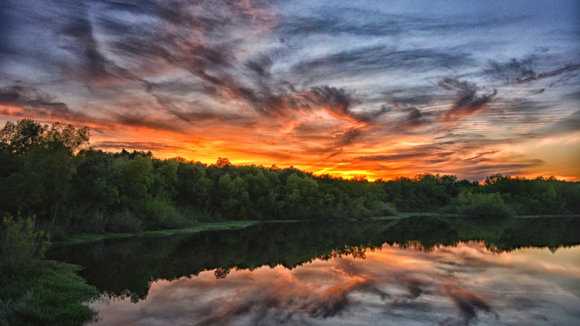 a lake with trees and a sunset