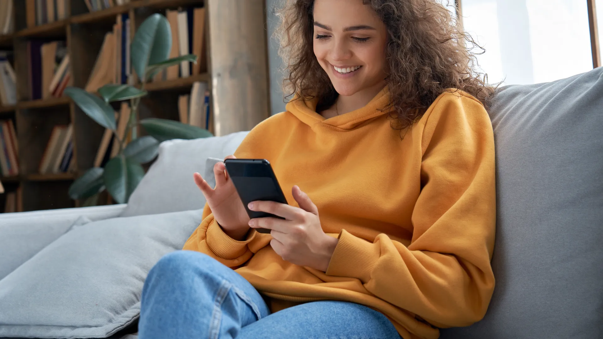 a person sitting on a couch and looking at a phone