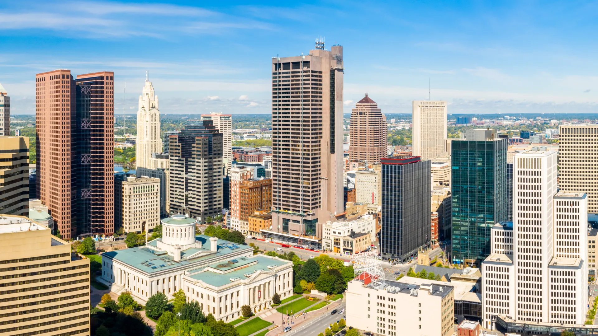 Panoramic view of downtown Columbus Ohio skyline with modern skyscrapers and historic buildings under blue sky