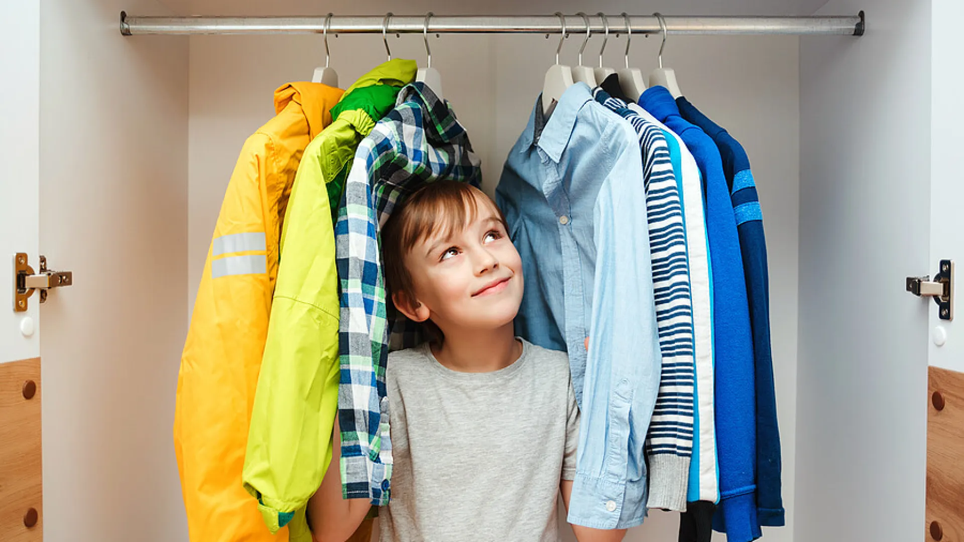 a boy standing in front of a rack of clothes